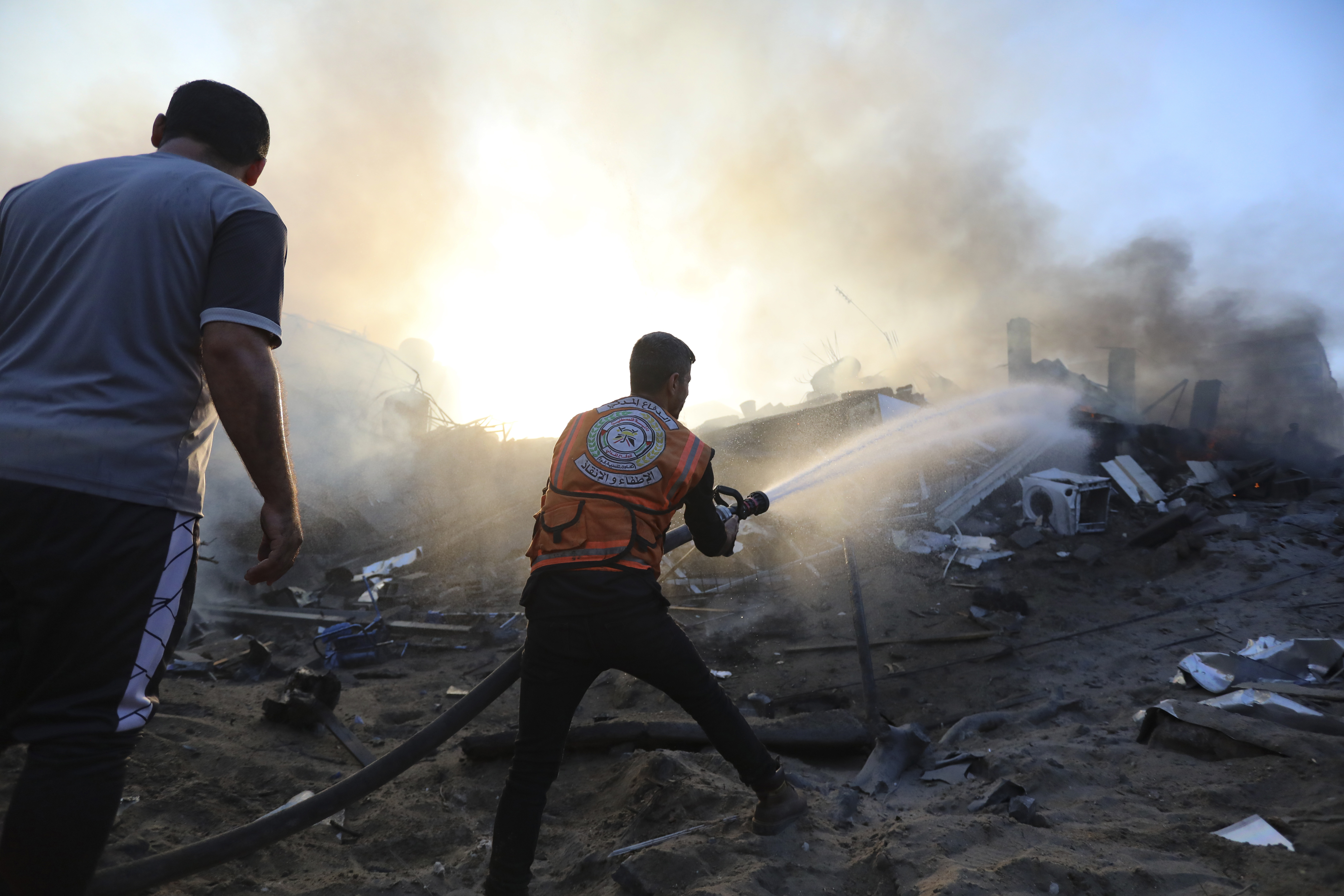 A Palestinian firefighter extinguishes a fire in a destroyed building following Israeli airstrikes