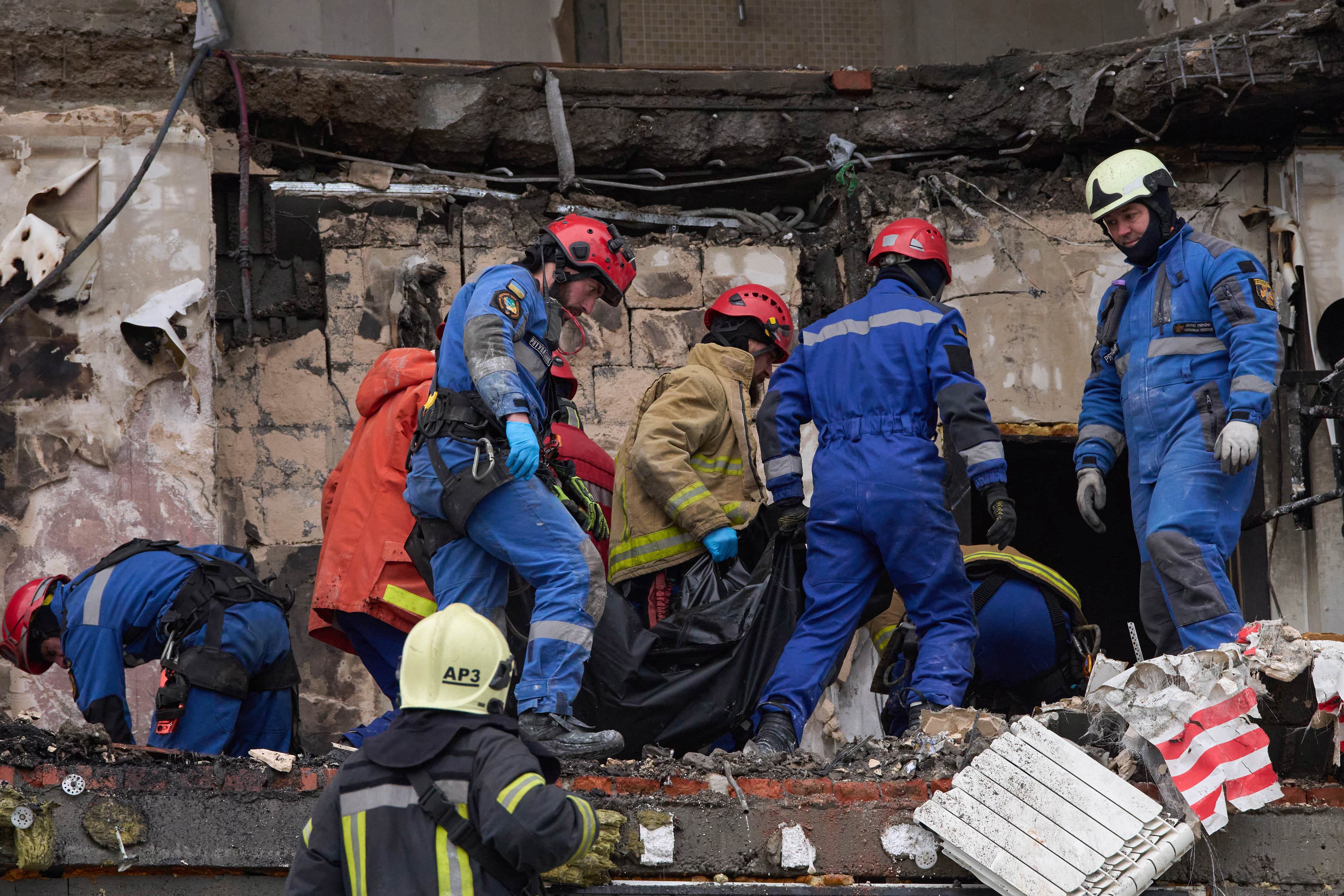 Rescuers carry the body of a victim after Russian drone hit a multi-storey apartment building during a massive missile and drone attack in Kyiv, Ukraine, Saturday, Dec. 27, 2025. (AP Photo/Efrem Lukatsky)