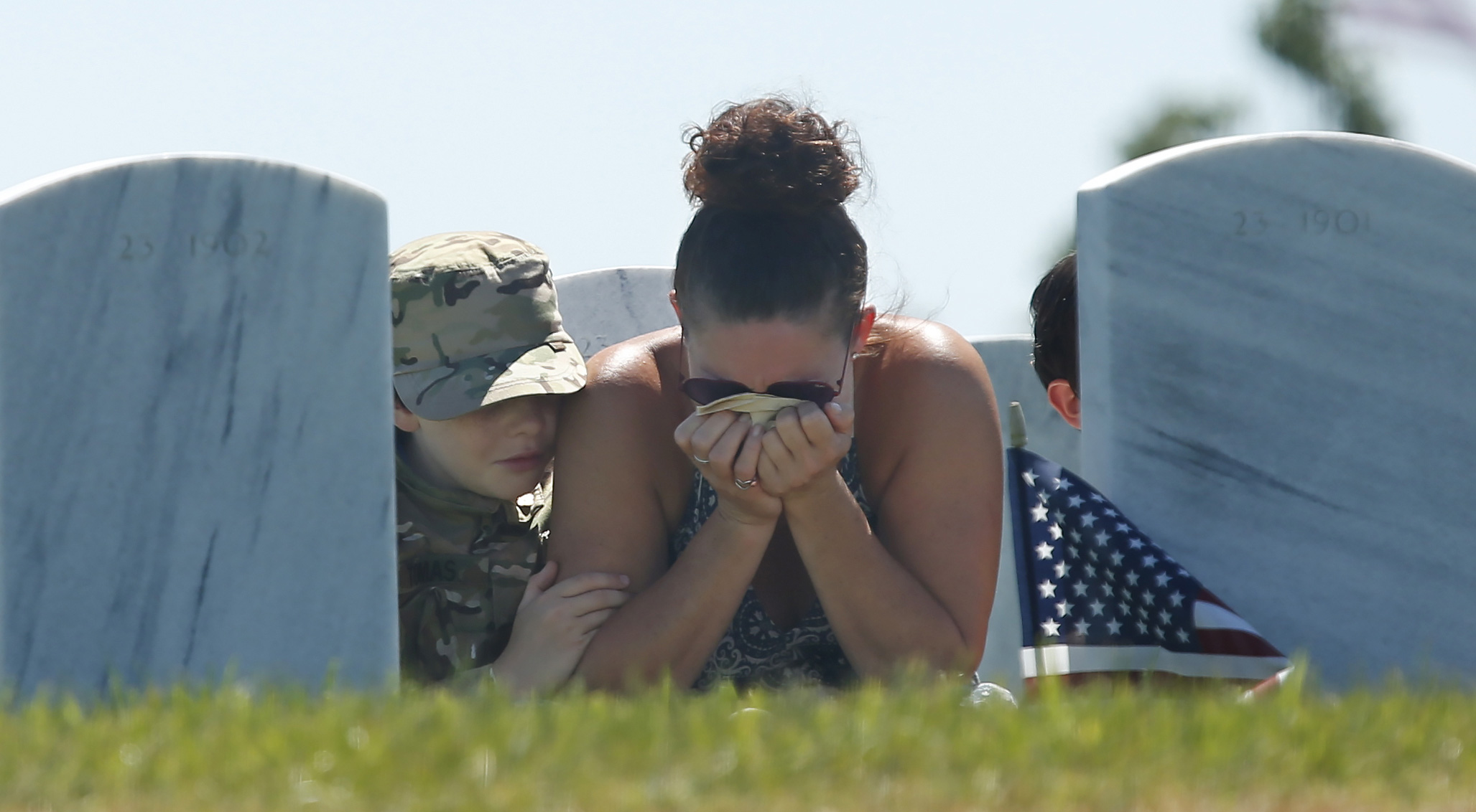 Heidi Hannah holds her head in her hands, as she is joined by her sons Tomas, 10, left, and Lucas, 8, right, at a Memorial Day visit to the grave of her oldest son, Army Specialist Taylor Hannah, at the Sacramento Valley National Cemetery in Dixon, California