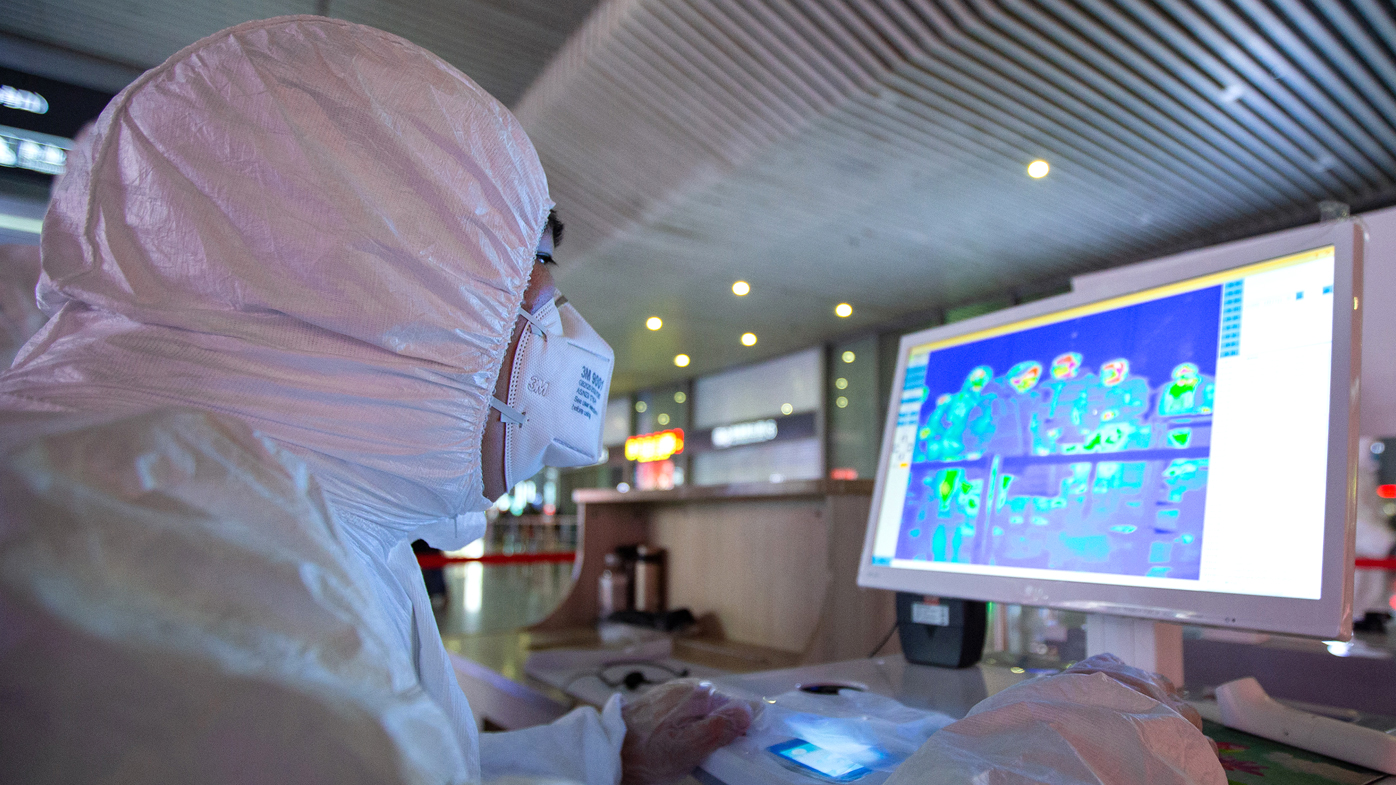 Chinese medical workers wearing protective clothing monitor body temperatures of passengers on a display for prevention of the new coronavirus at the Nanjing South Railway Station