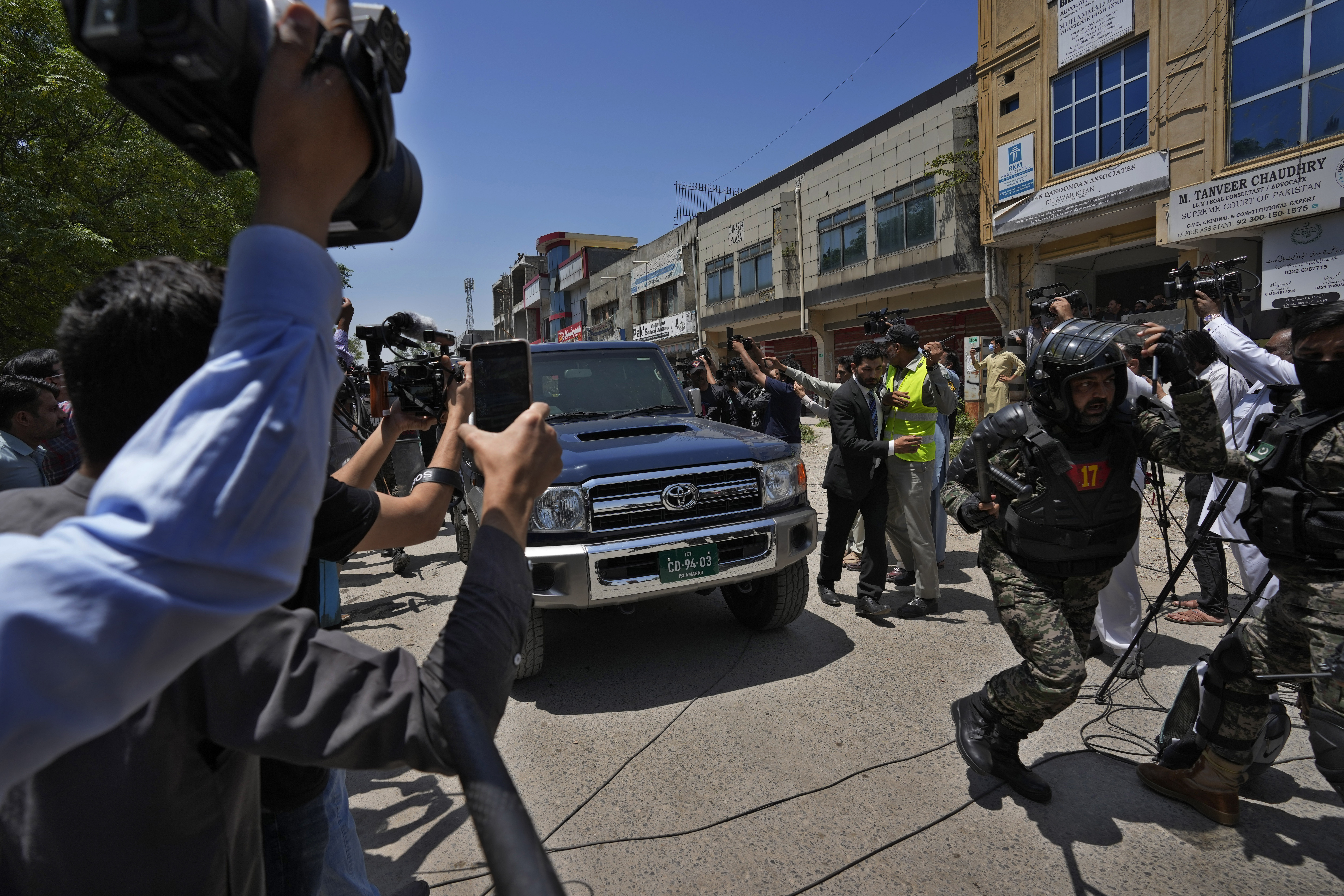 A paramilitary soldier clears the way for a vehicle carrying Pakistan's former Prime Minister Imran Khan as he arrives to appear in a court, in Islamabad, Pakistan, Friday, May 12, 2023