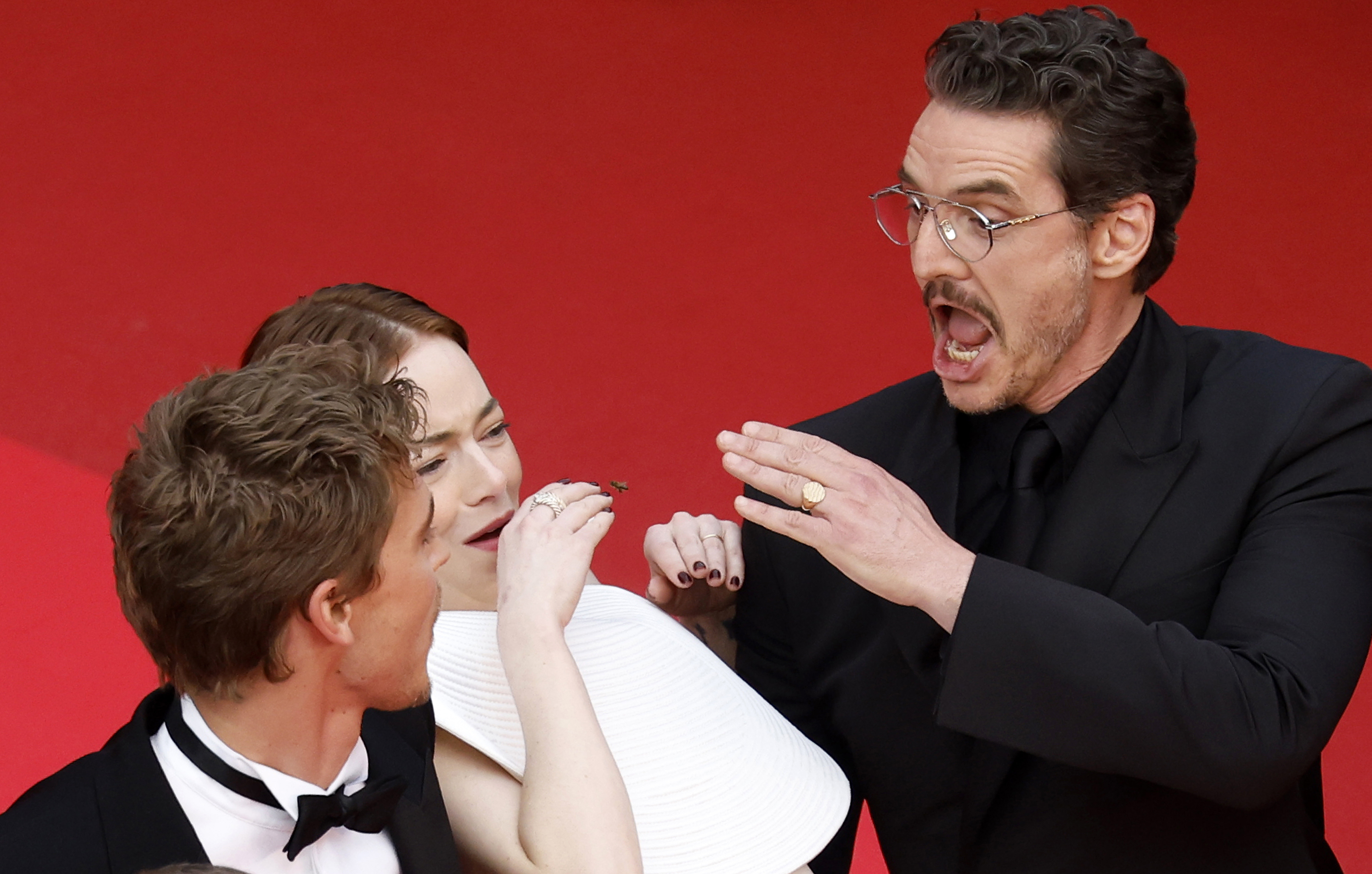 Emma Stone tries to avoid a bee next to Austin Butler and Pedro Pascal at the premiere of Eddington during the 78th annual Cannes Film Festival, in Cannes, France, 16 May 2025 