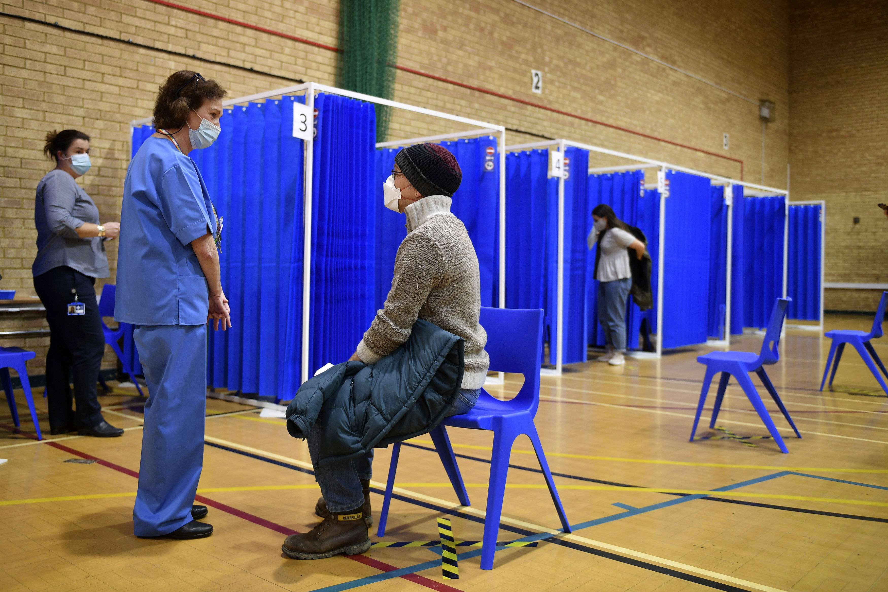 A nurse speaks to a man before administering the Pfizer/BioNTech Covid-19 vaccine at a vaccination centre in Cardiff on the first day of the largest immunisation programme in the UK's history.