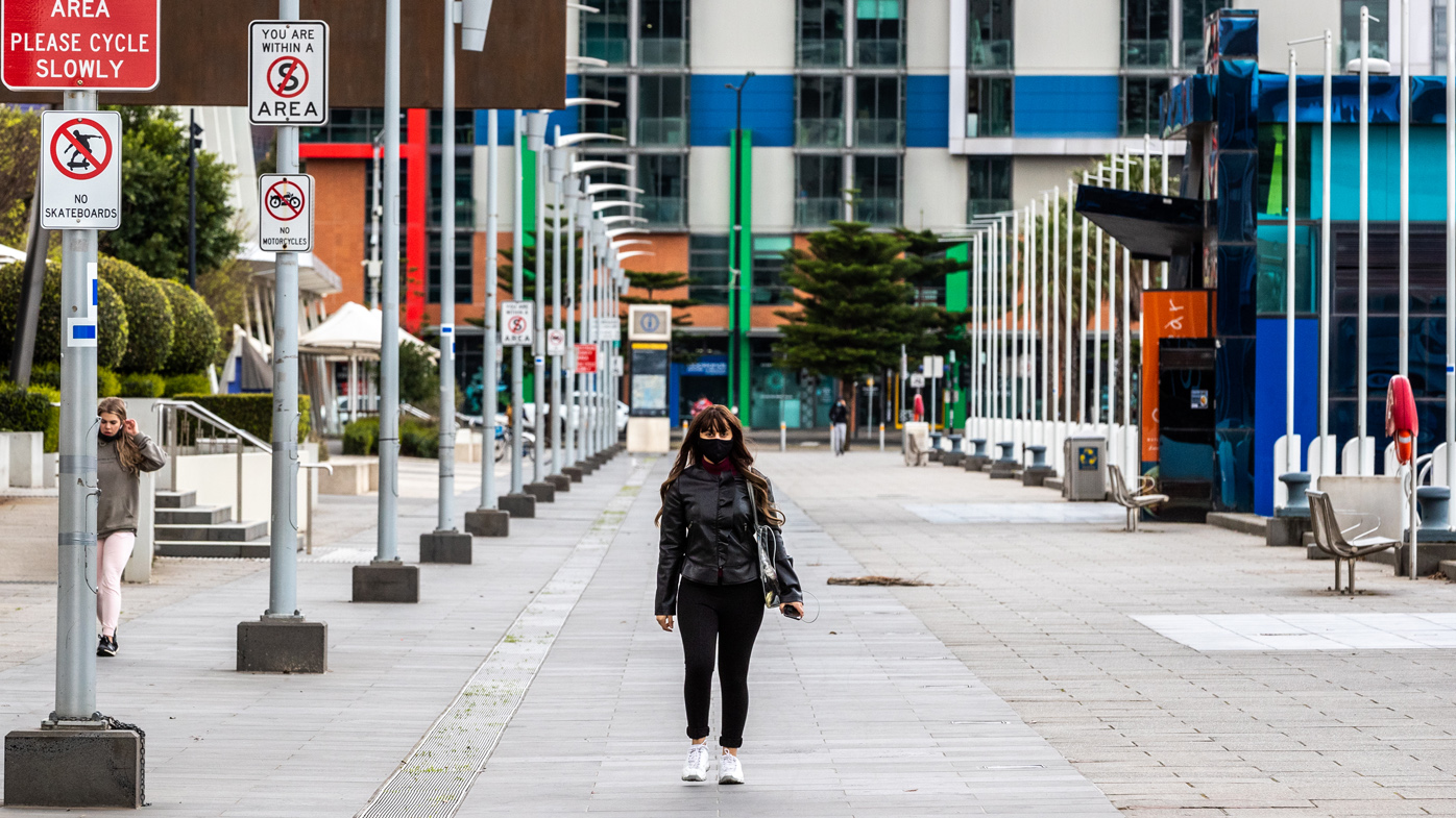 A lone pedestrian walks along a street in the Docklands precinct on September 25, 2020 in Melbourne, Australia. 