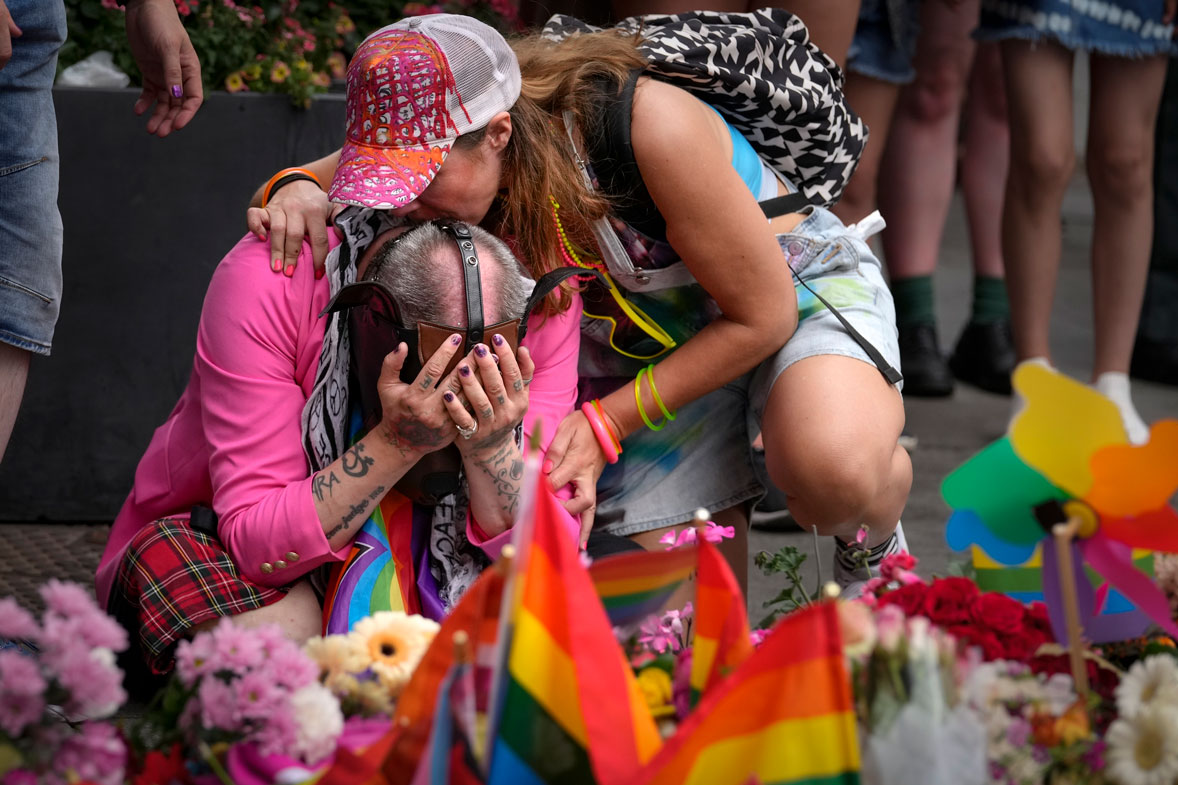 People react laying flowers at the scene of a shooting in central Oslo, Norway, Saturday, June 25, 2022. 