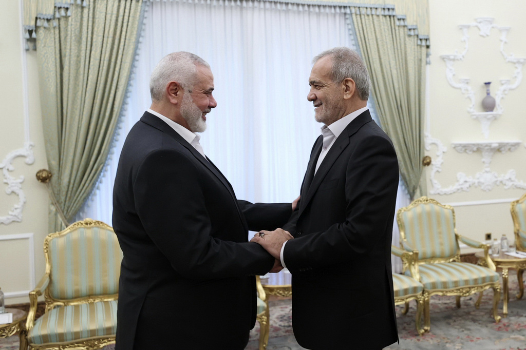 In this photo released by the Iranian Presidency Office, President Masoud Pezeshkian, right, shakes hands with Hamas chief Ismail Haniyeh