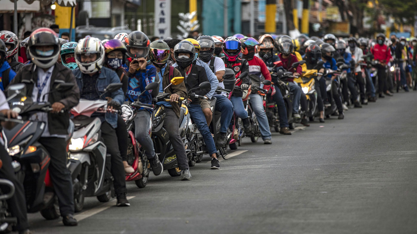 Motorcyclists outside Manila queue up for a health check before they are allowed into the city.