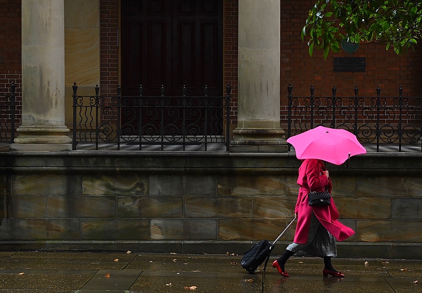 Widespread rain and thunderstorms are predicted for parts of Australia for the next four days.A woman wearing a pink coat and carrying a pink umbrella walks through the rain past St James Church in the Sydney CBD, NSW. 17th March, 2021. Photo: Kate Geraghty