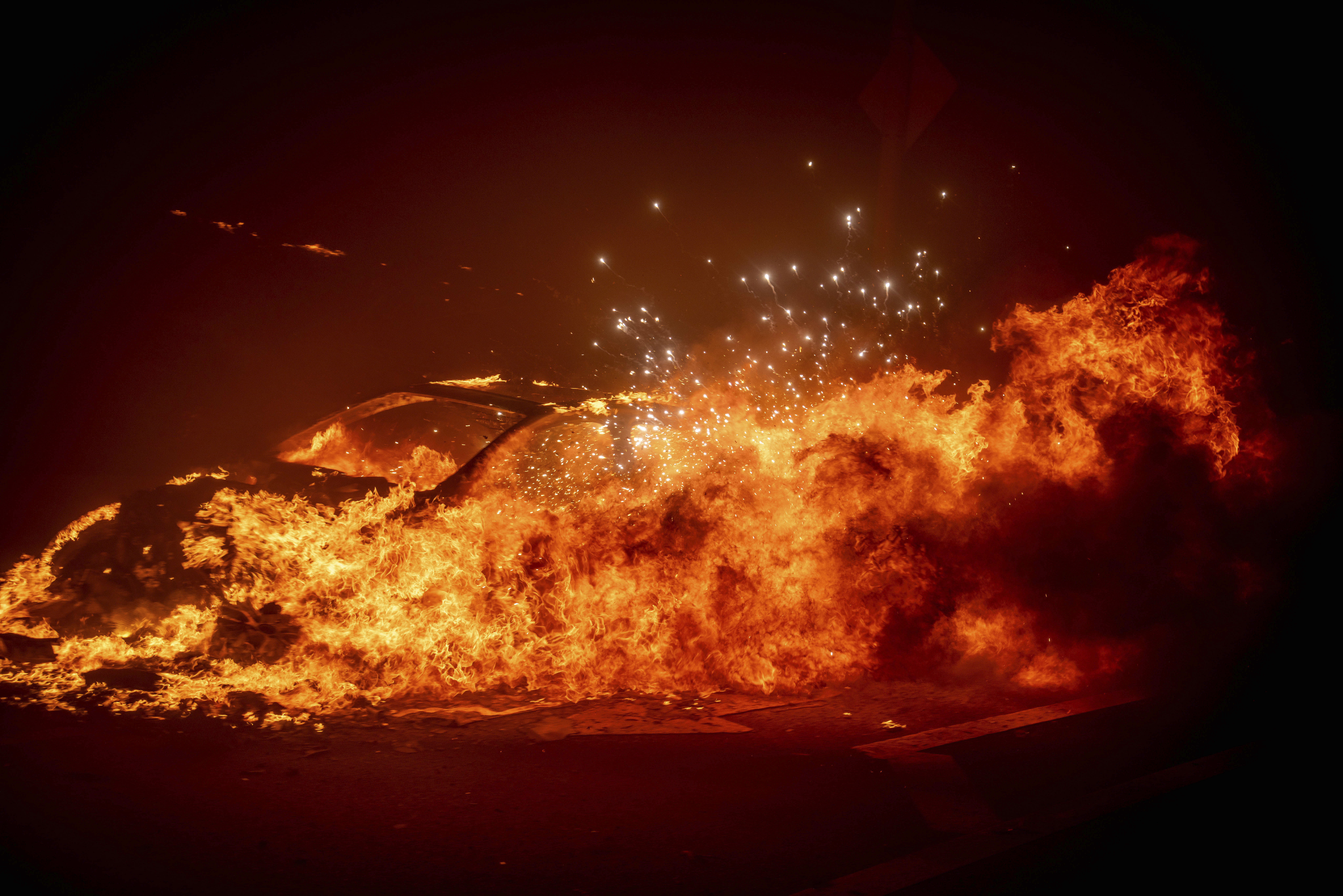 A vehicle burns as the Palisades Fire advances in the Pacific Palisades neighborhood of Los Angeles, Tuesday, Jan. 7, 2025. (AP Photo/Ethan Swope)