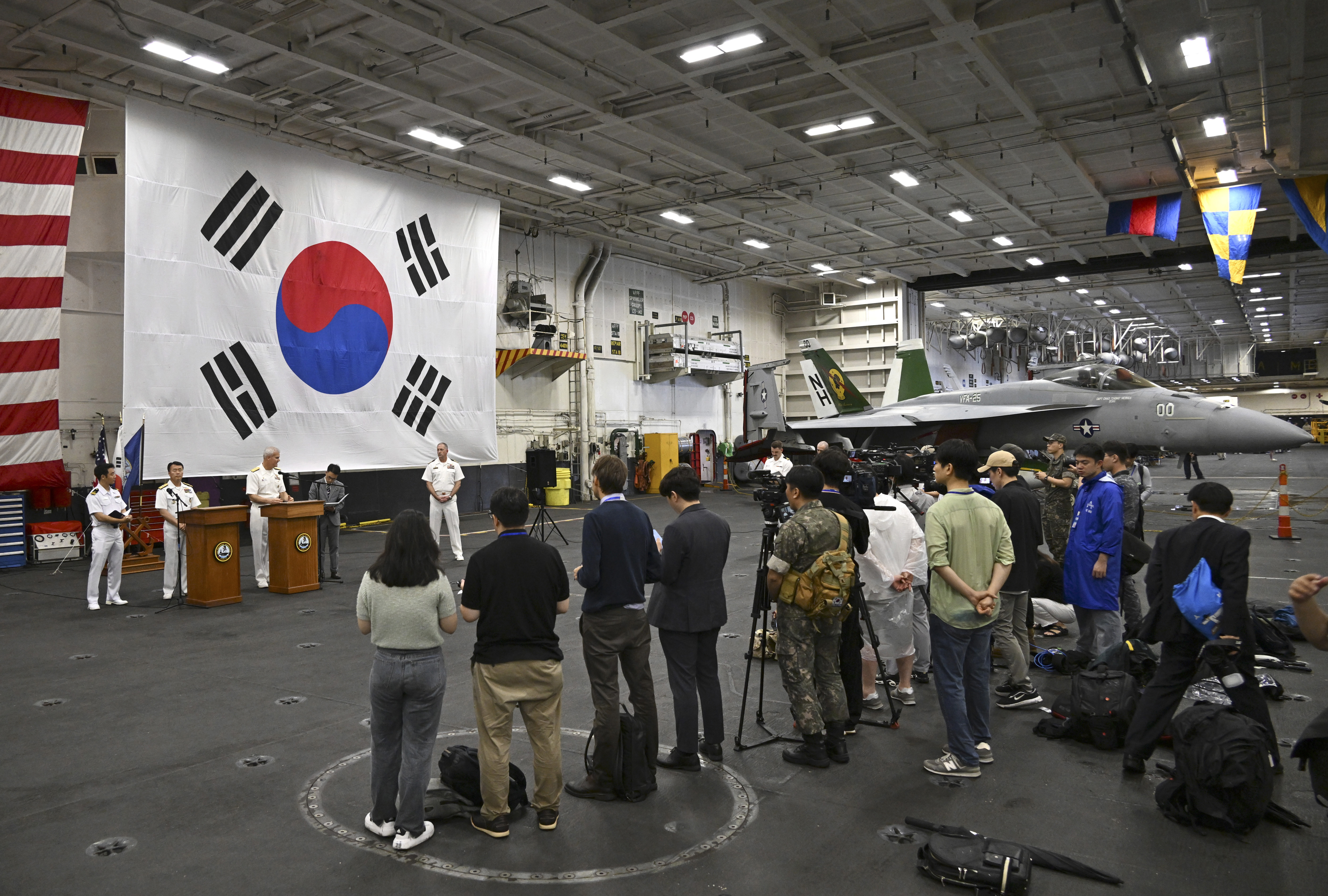 Miembros de la tripulación y miembros de los medios de comunicación se reúnen en el hangar del Theodore Roosevelt (CVN 71), un portaaviones de propulsión nuclear, anclado en la Base Naval de Busan, en Busan, Corea del Sur, el sábado 22 de junio de 2024.