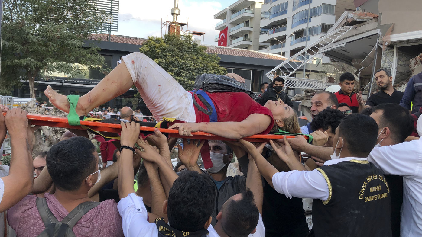 Rescue workers and local people carry a wounded person found in the debris of a collapsed building, in Izmir, Turkey, Friday, Oct. 30, 2020, after a strong earthquake in the Aegean Sea has shaken Turkey and Greece