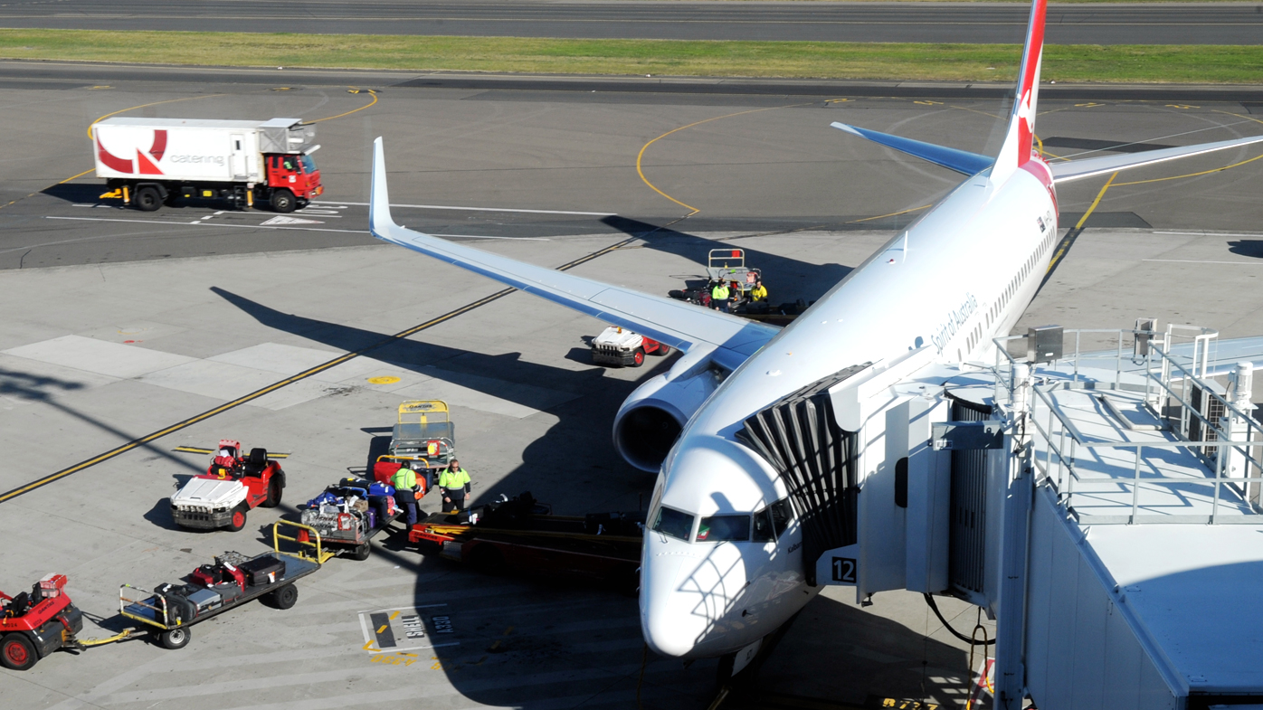 Baggage handlers unload luggage from a Qantas plane. 