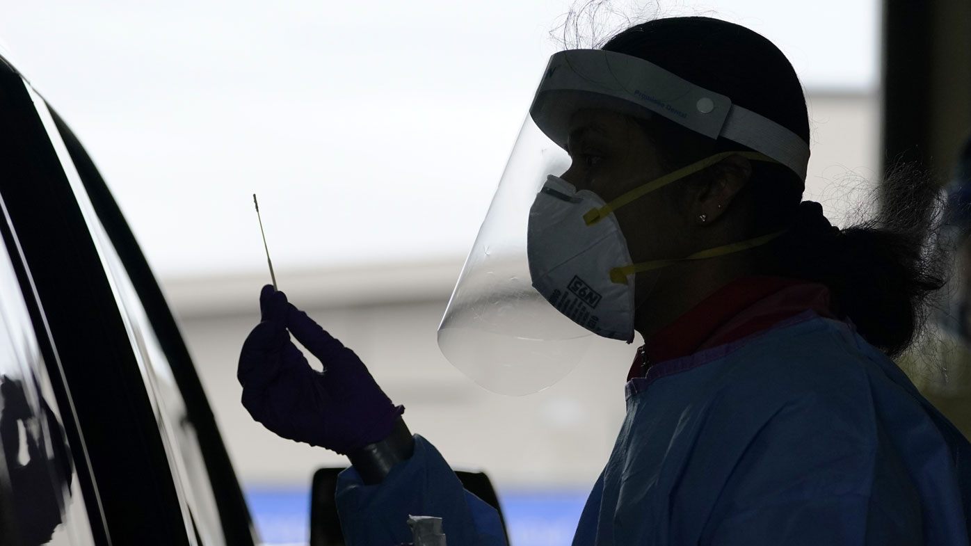 University of Washington research coordinator Rhoshni Prabhu holds up a swab after testing a passenger at a free COVID testing site in Seattle.