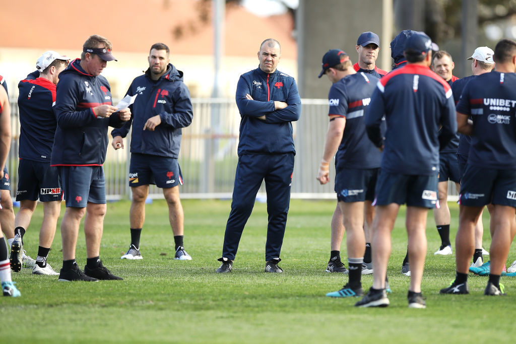 Michael Cheika looks on as Roosters coach Trent Robinson gives instructions to the players.