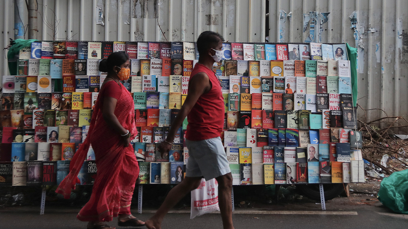 Indian people wearing masks as a precaution against the coronavirus walks in front of books stall kept for sale during Sunday market at a street in Hyderabad, India, Sunday, July 19, 2020. India crossed 1 million coronavirus cases on Friday, third only to the United States and Brazil, prompting concerns about its readiness to confront an inevitable surge that could overwhelm hospitals and test the country's feeble health care system. (AP Photo/Mahesh Kumar A.)