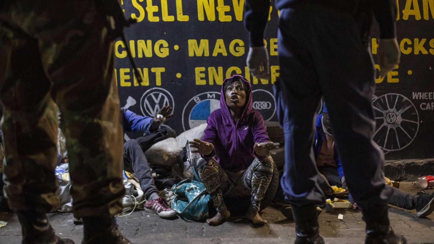 A homeless woman is confronted by soldiers in Johannesburg, South Africa.