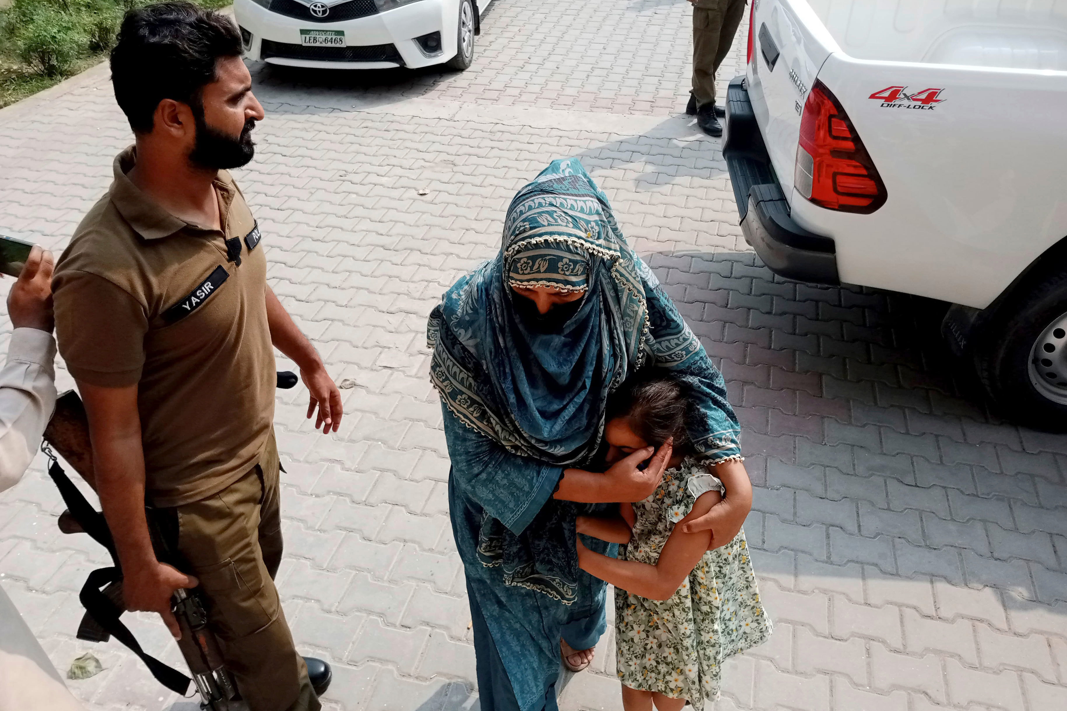 Police officers escort a relative and child of a couple who are wanted by British police in connection with the death of Sara Sharif, aged 10.