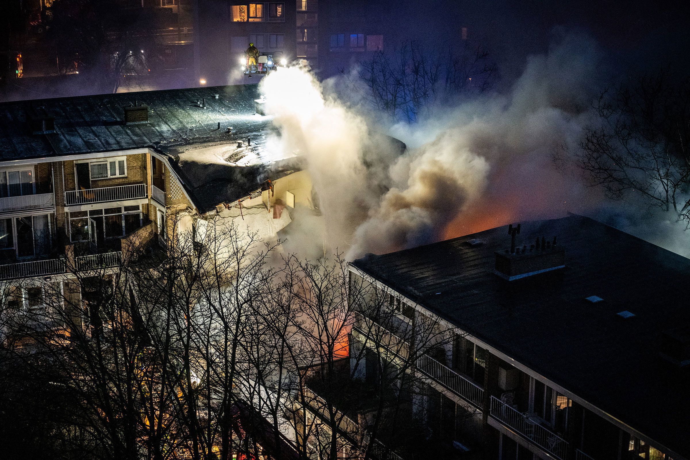 Firemen try to douse a fire following an explosion at a residential building in The Hague