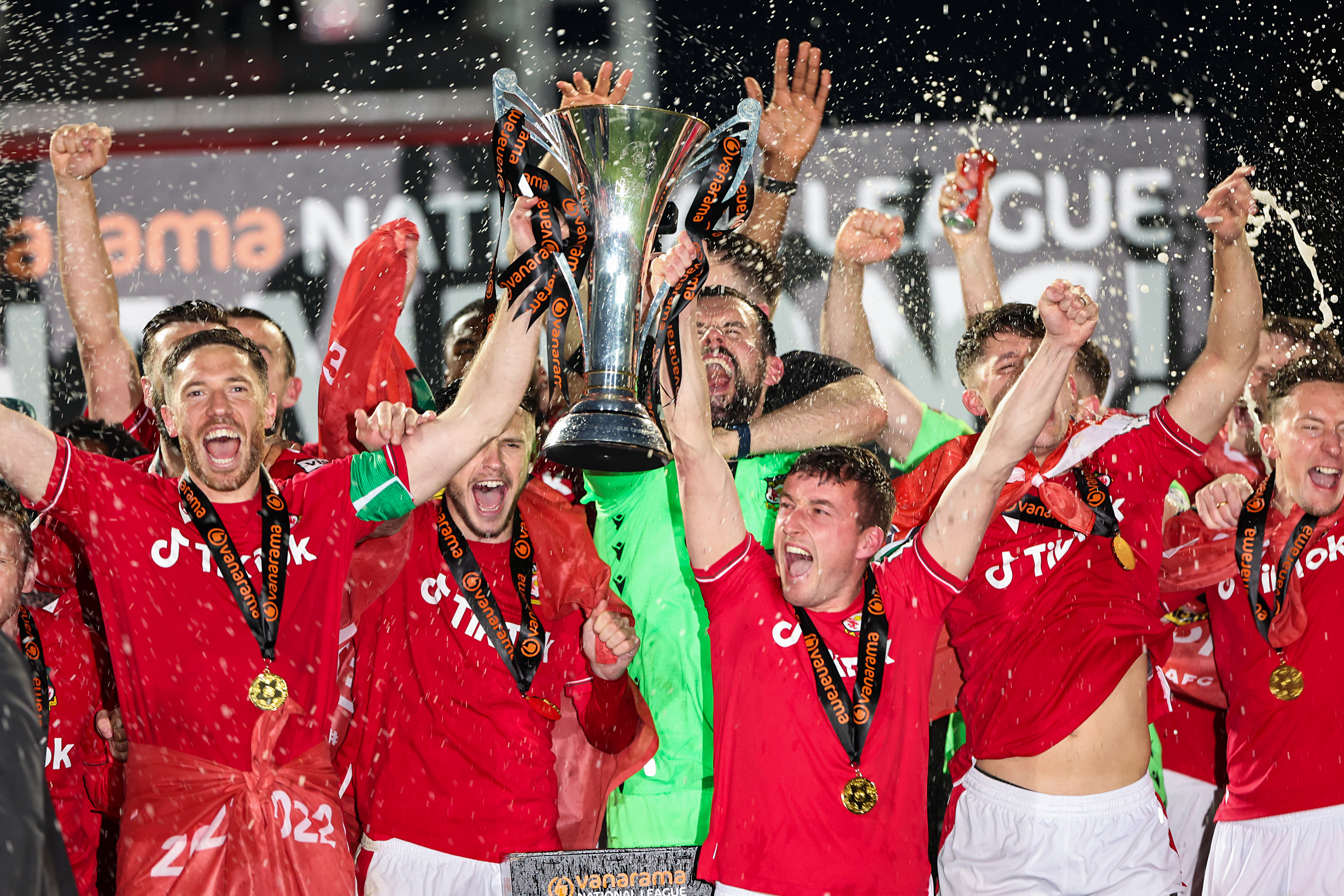 Ben Tozer and Luke Young of Wrexham lift the Vanarama National League Trophy as Wrexham celebrate promotion back to the English Football League during the Vanarama National League match between Wrexham and Boreham Wood at Racecourse Ground on April 22, 2023 in Wrexham, Wales. (Photo by Matthew Ashton - AMA/Getty Images)