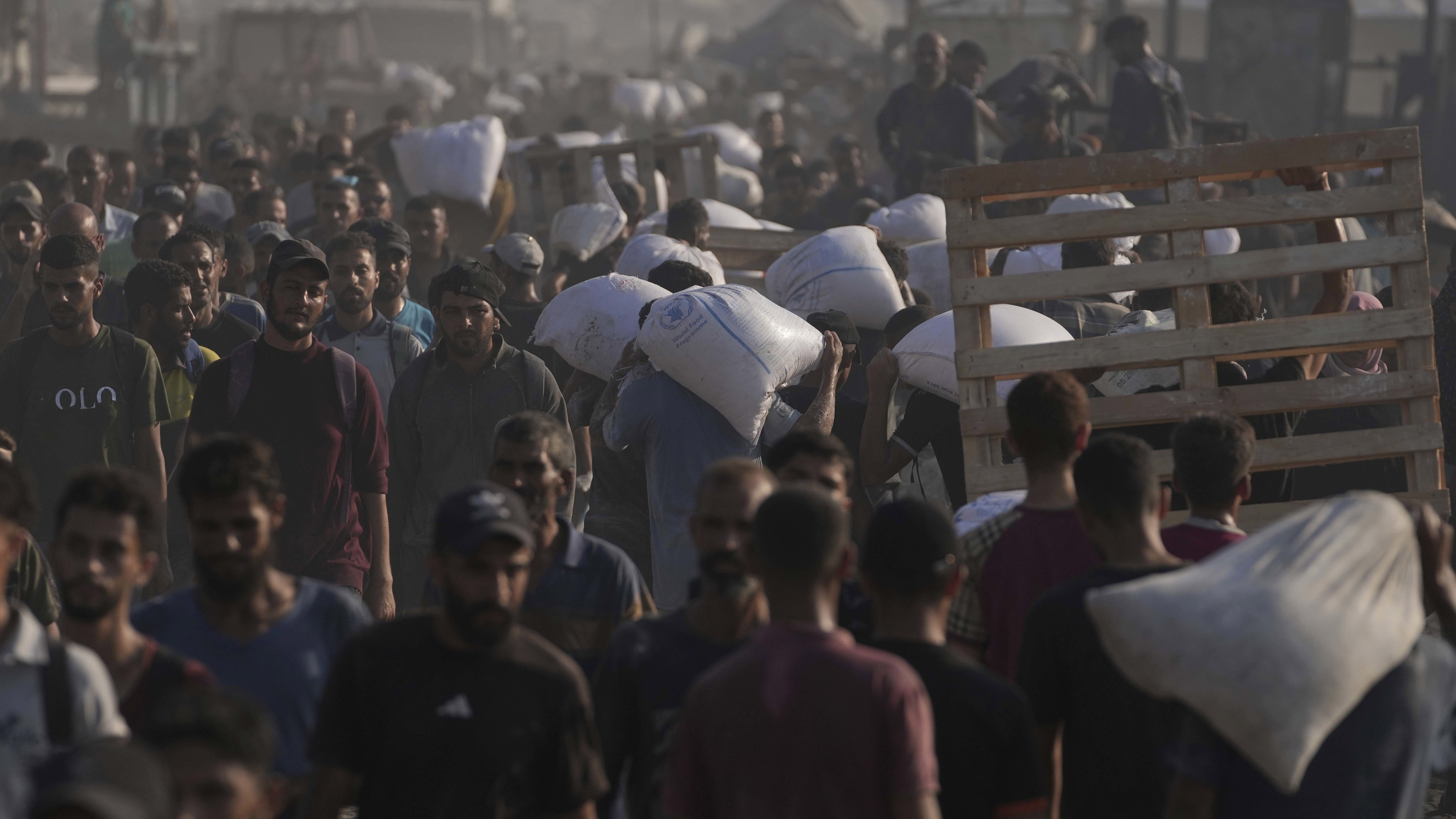 Palestinians carry sacks of flour unloaded from a humanitarian aid convoy that reached Gaza City from the northern Gaza Strip.