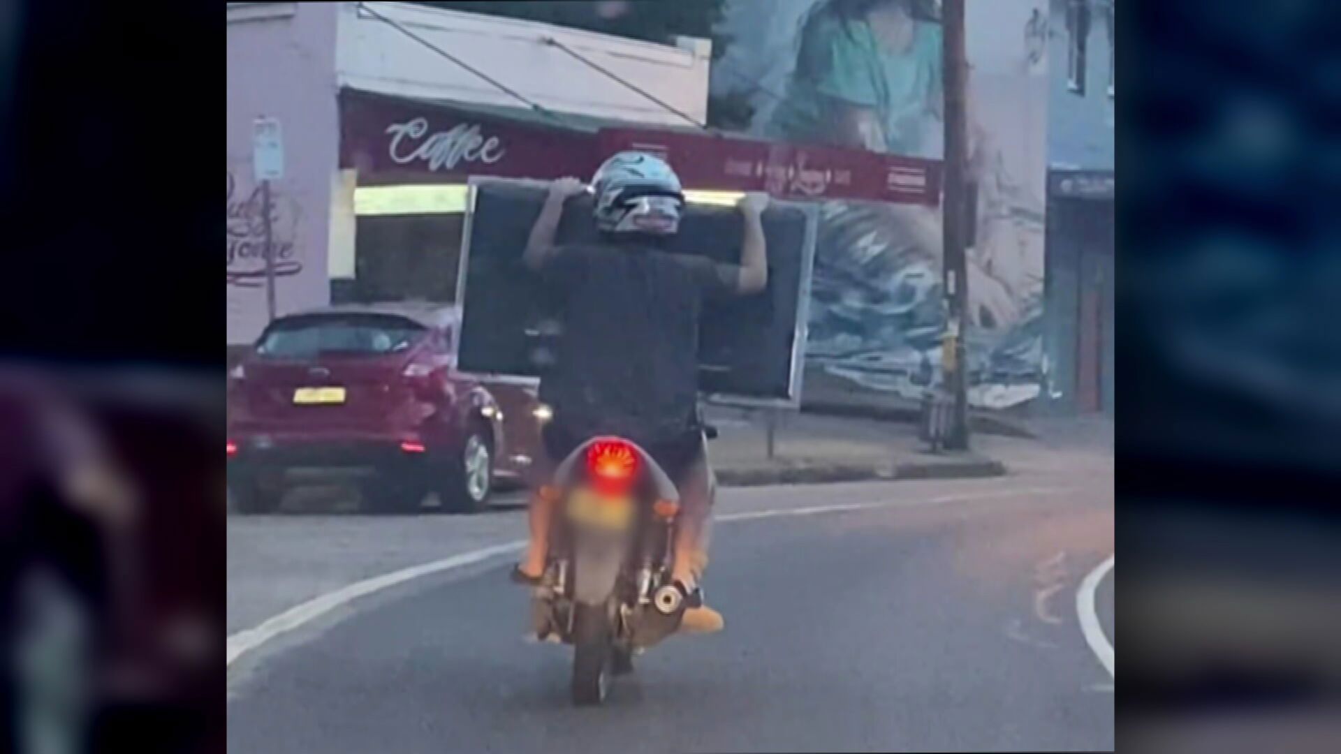 Two men on a scooter have been filmed hauling what appears to be a television in Sydney's Inner West.