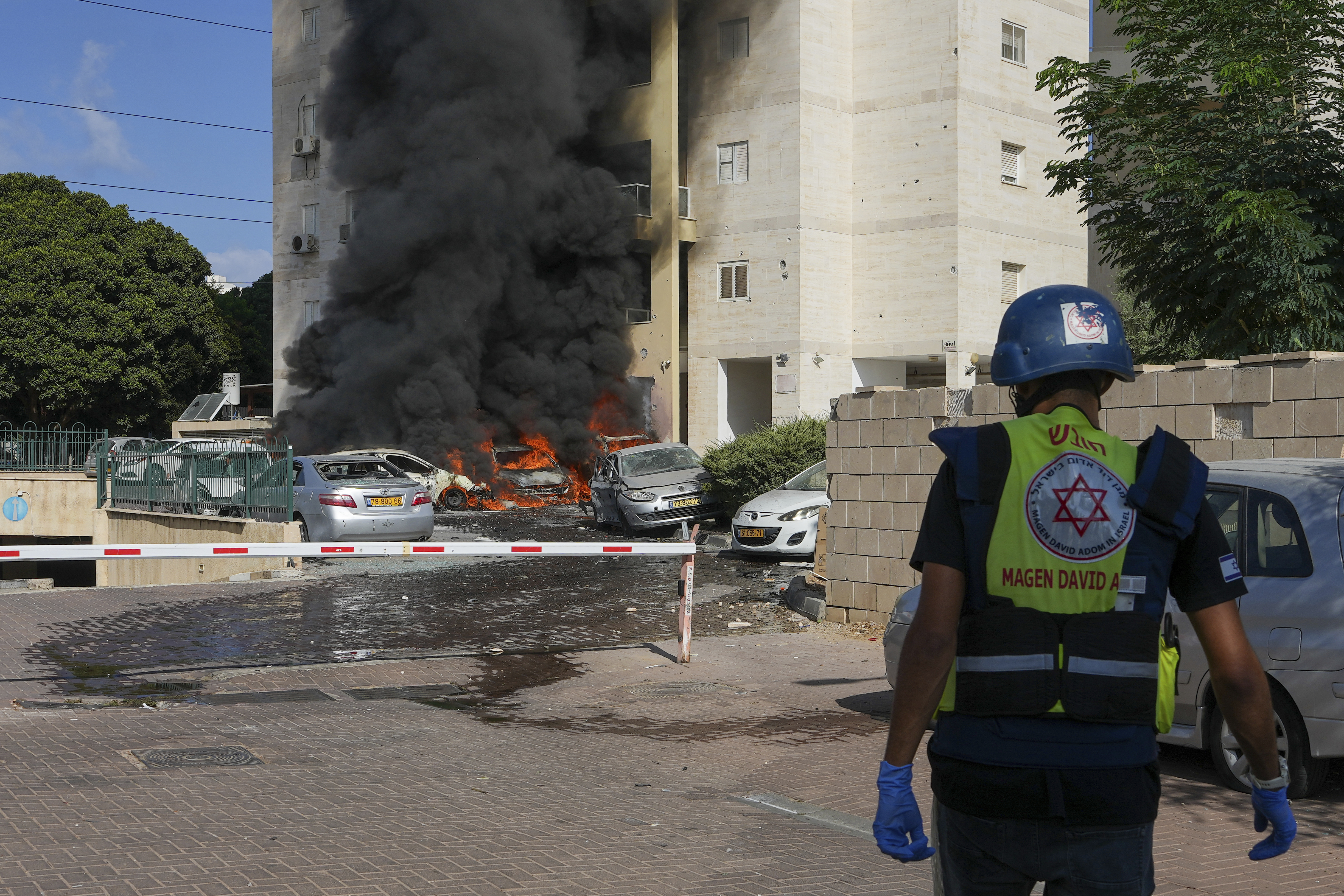 Cars are burning after a rocket fired from the Gaza Strip hit a parking lot and a residential building in Ashkelon, southern Israel, Saturday, Oct. 7, 2023. 