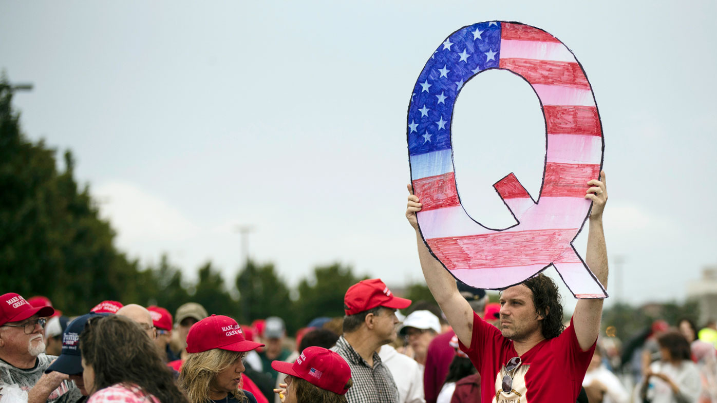A protesters holds a Q sign waits in line with others to enter a campaign rally with President Donald Trump in August 2014.