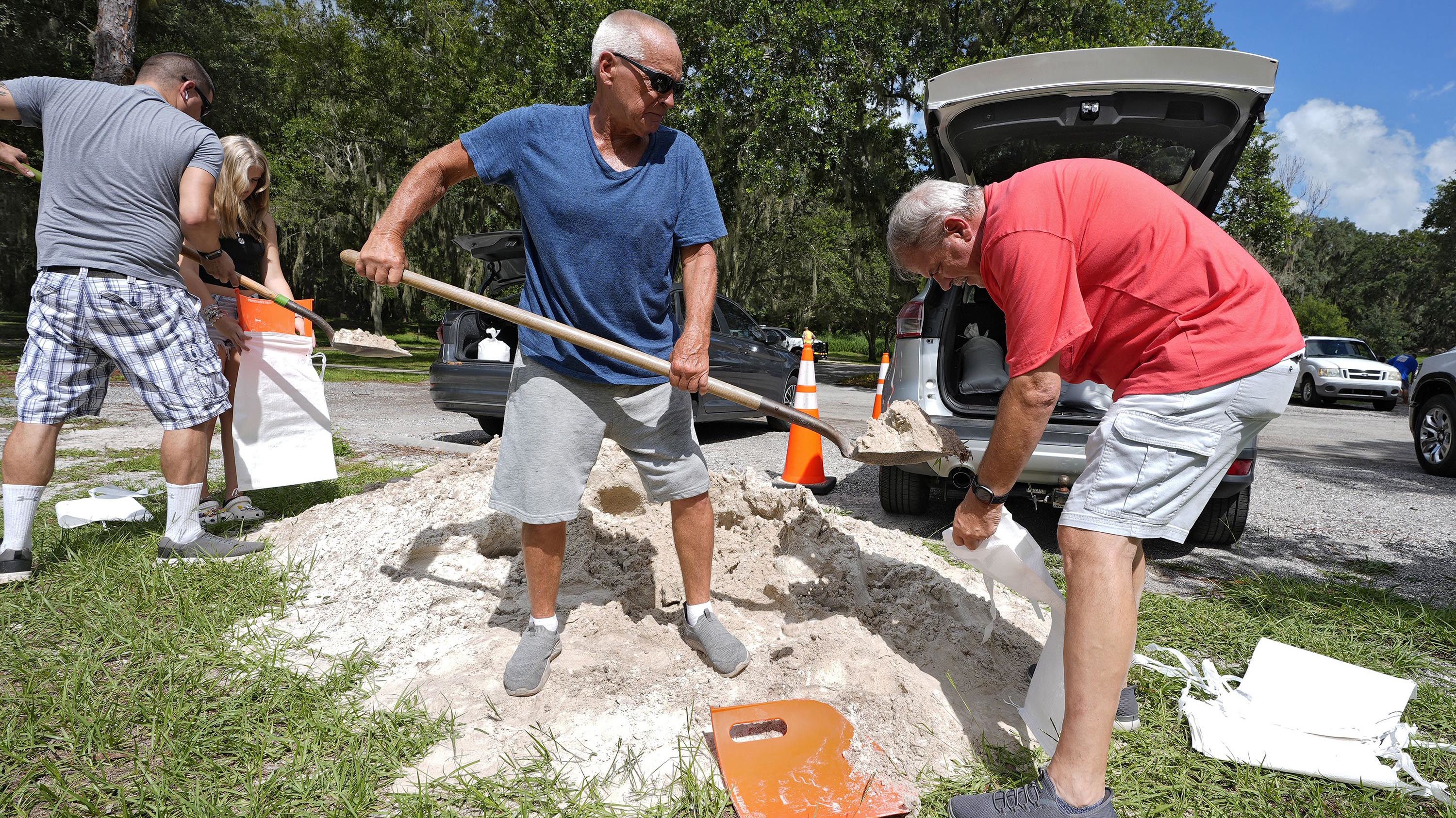 Roger Heim, a la derecha, y Terry Smith, en el centro, ambos de Valrico, Florida, llenan bolsas de arena en el Parque de Conservación Edward Medard en Plant City.