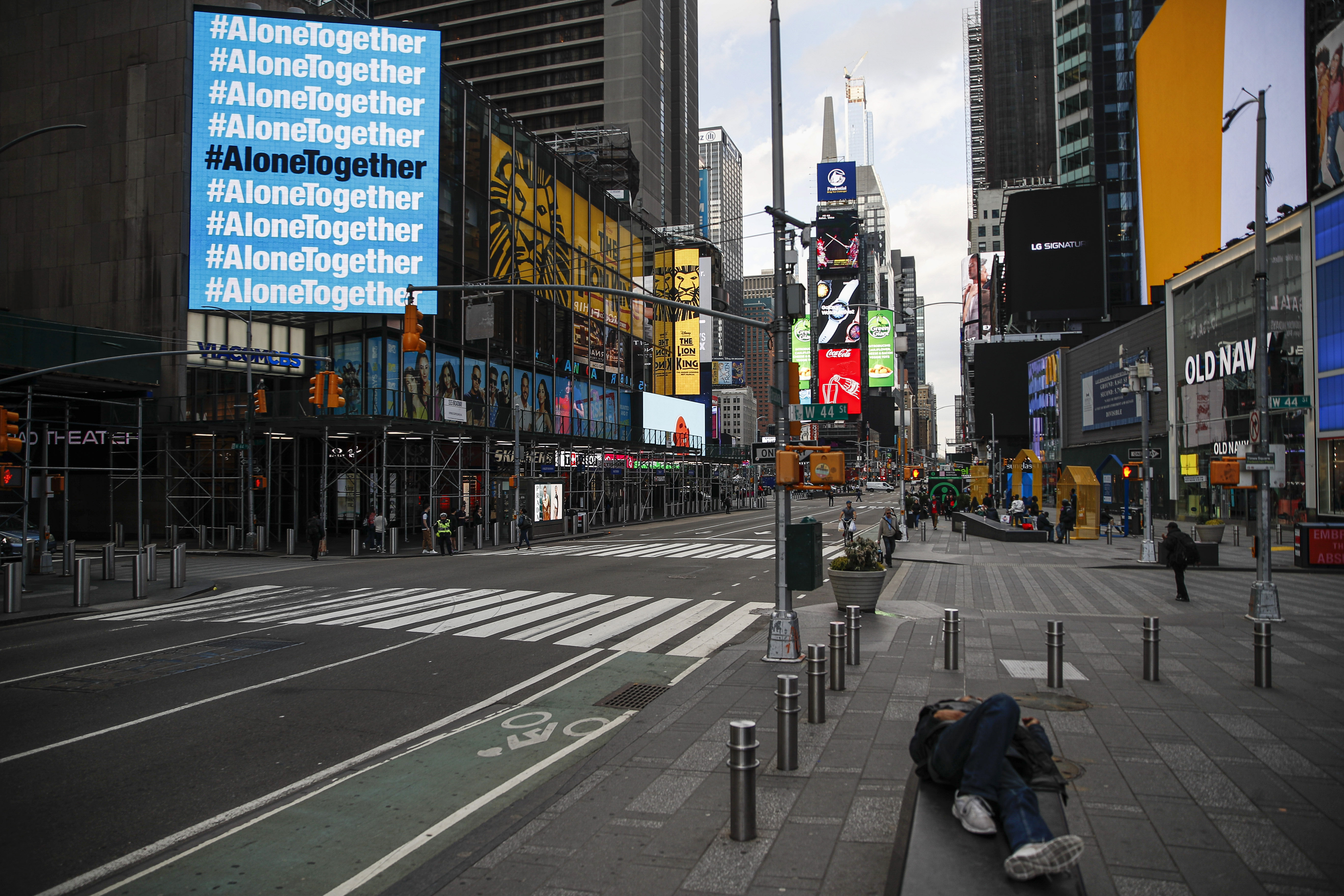 A billboard displaying hashtags concerning COVID-19 hangs over a sparsely populated Times Square, Friday, March 20, 2020, in New York. New York Gov. Andrew Cuomo is ordering all workers in non-essential businesses to stay home and banning gatherings statewide. Only essential businesses can have workers commuting to the job or on the job, Cuomo said of an executive order he will sign Friday. Nonessential gatherings of individuals of any size or for any reason are canceled or postponed. (AP Photo/