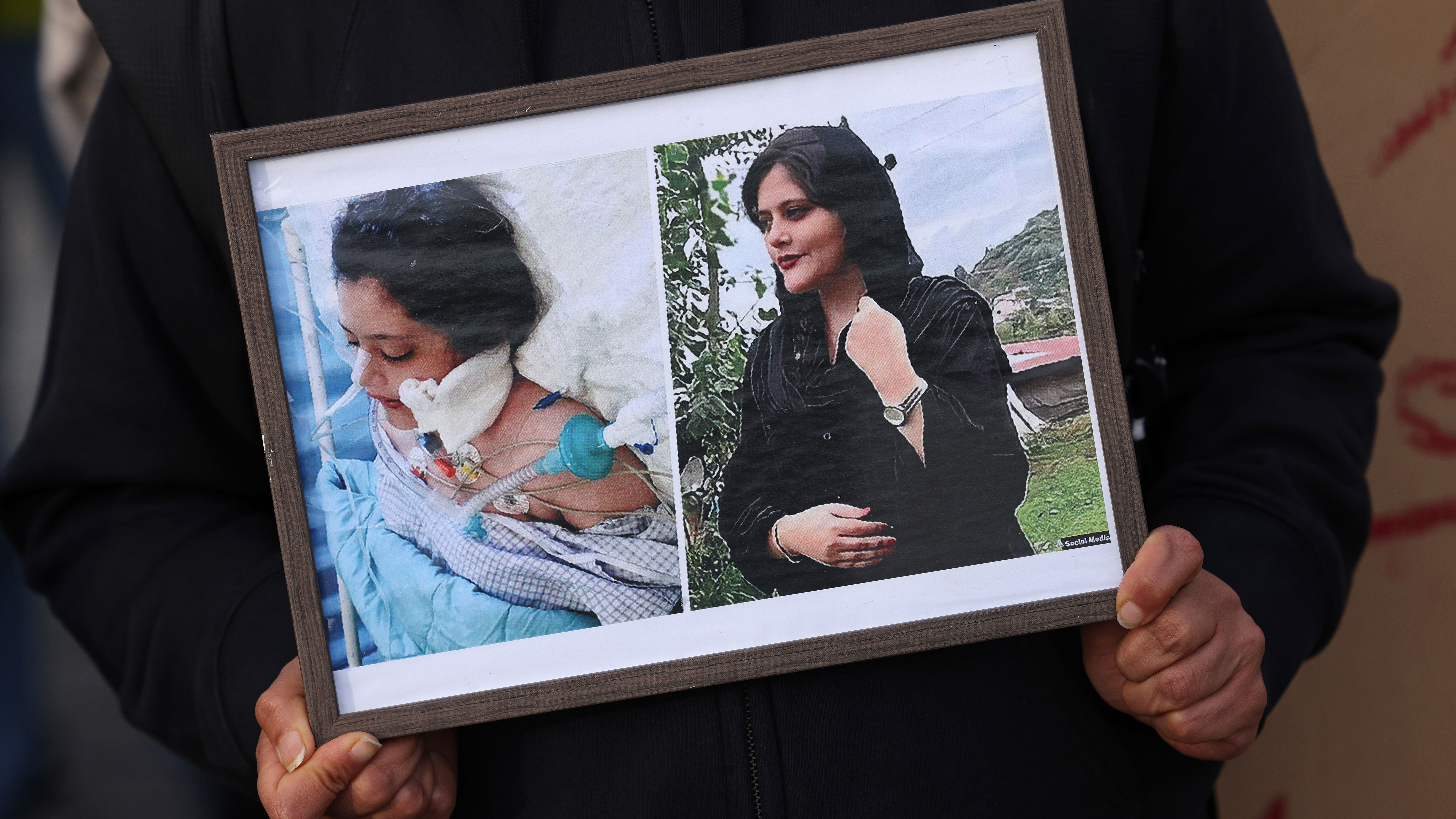 A protester in Germany holds photographs of Mahsa Amini during a demonstration against the death of Amini.
