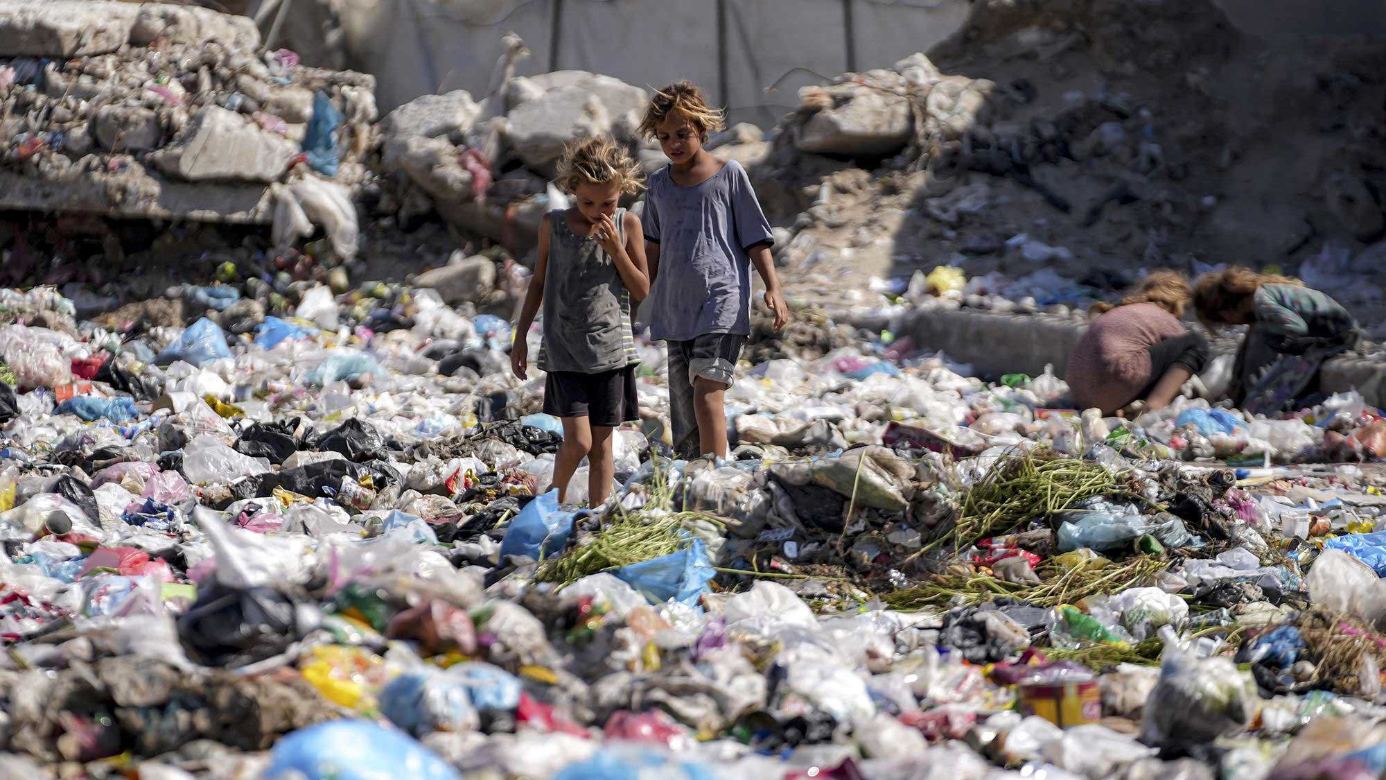 Displaced children sort through trash at a street in Deir Al-Balah, central Gaza Strip, on August 29.