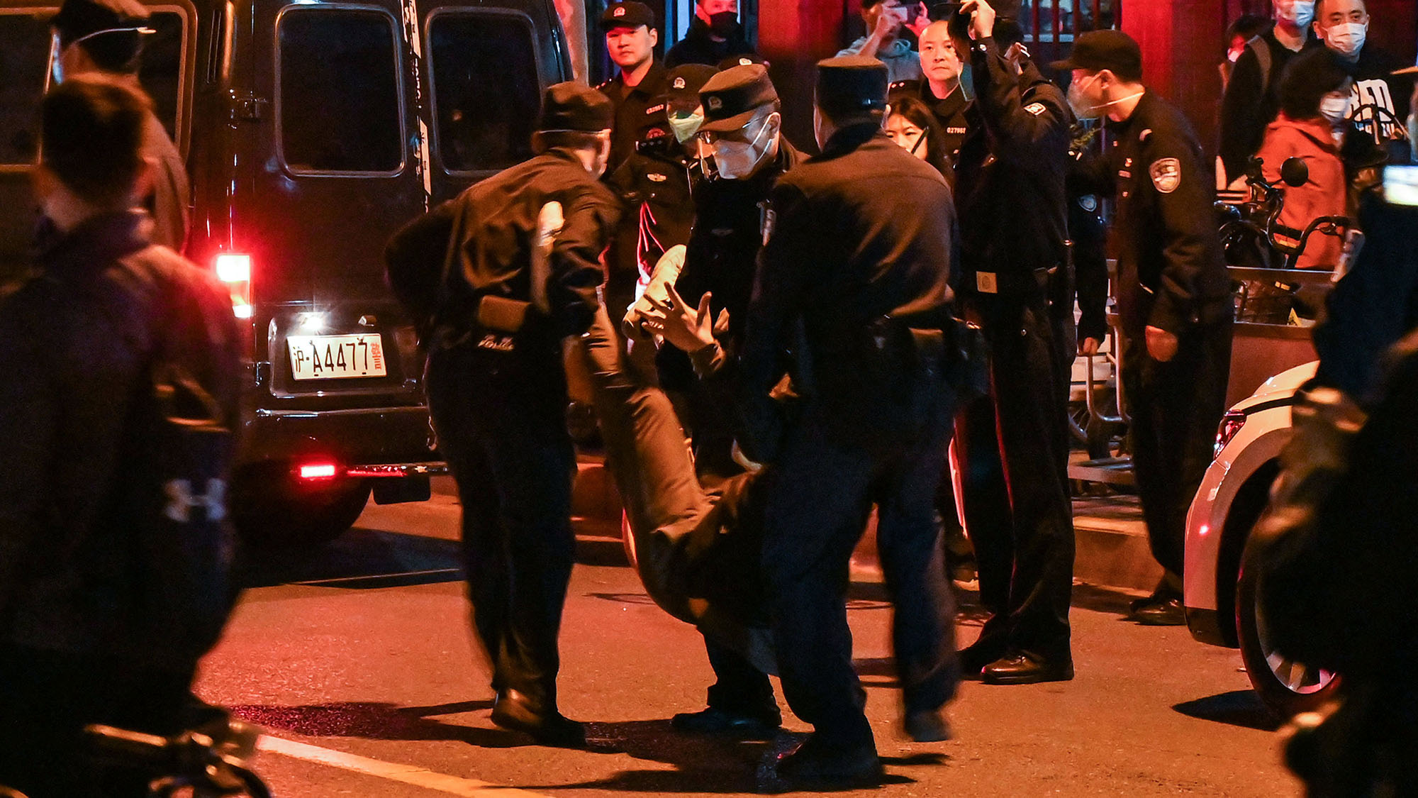 Un hombre es arrestado mientras la gente se reúne en una calle de Shanghái el 27 de noviembre.