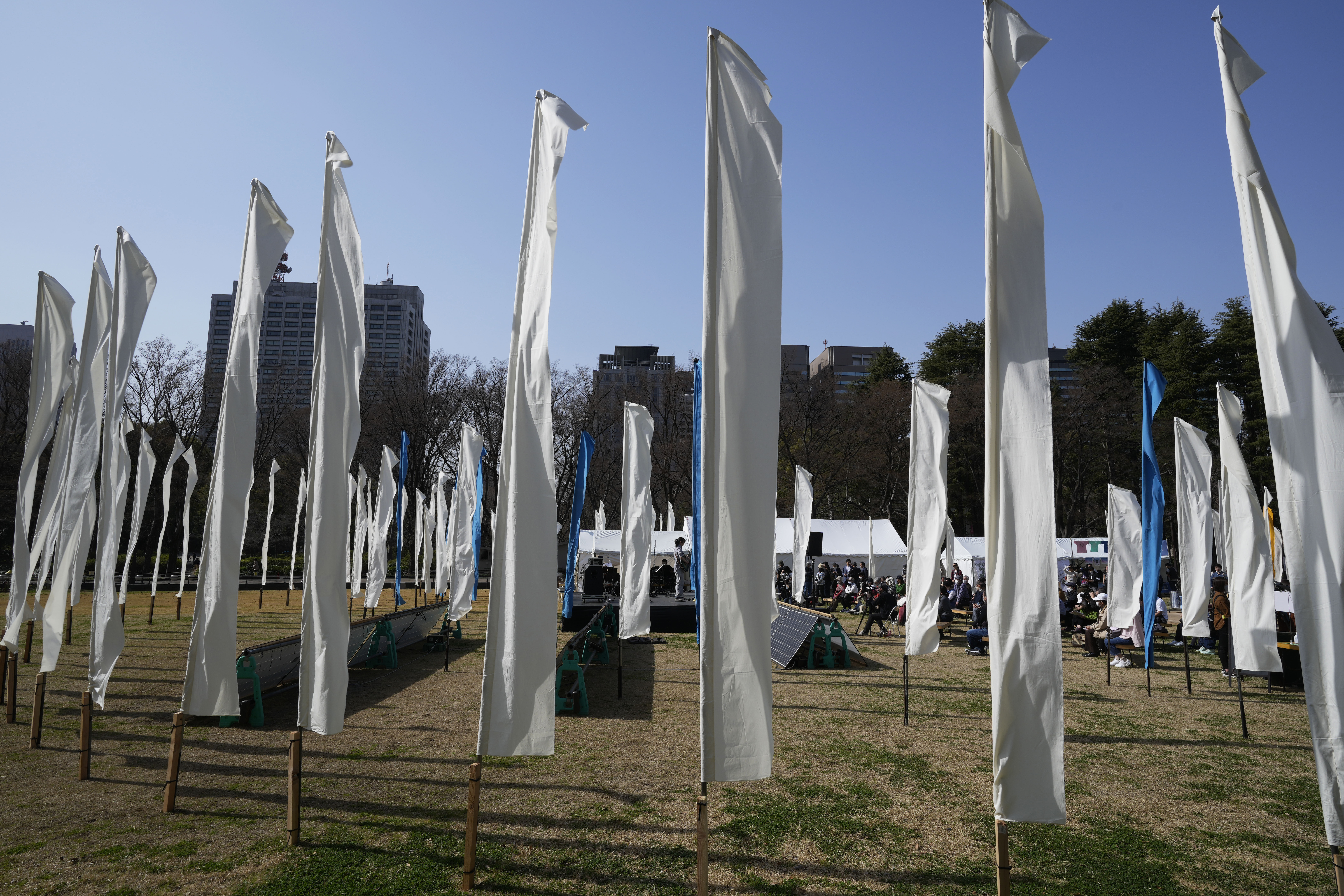 Artists perform on stage surrounded by decorations of "peace flags" to commemorate the 311 disaster following an earthquake and tsunami in the Tohoku region 12 years ago, during an anniversary event at Hibiya Park in Tokyo, Saturday, March 11, 2023.
