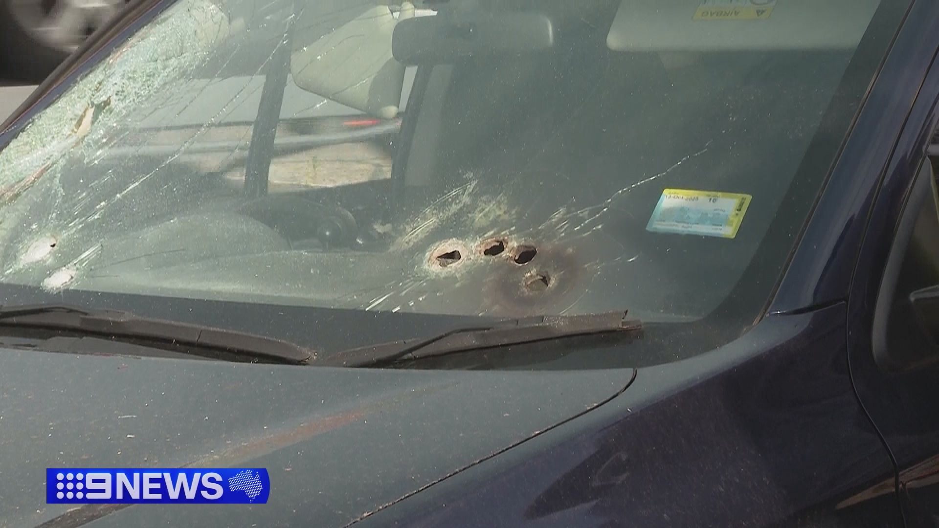 A car with multiple bullet holes in the windshield.