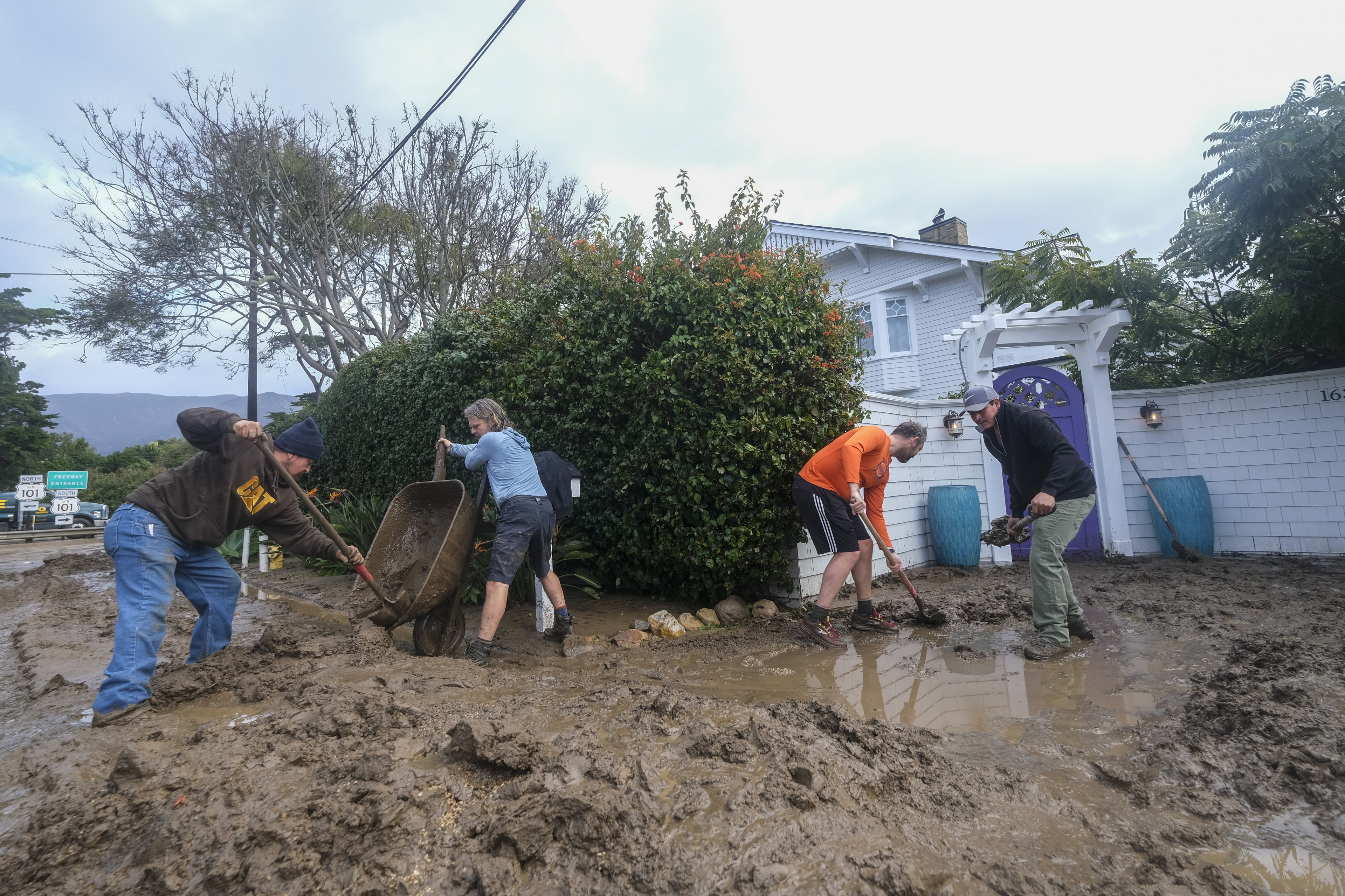 People shovel mud from the front of a home near Highway 101 in Montecito, Calif., Tuesday, Jan. 10, 2023.
