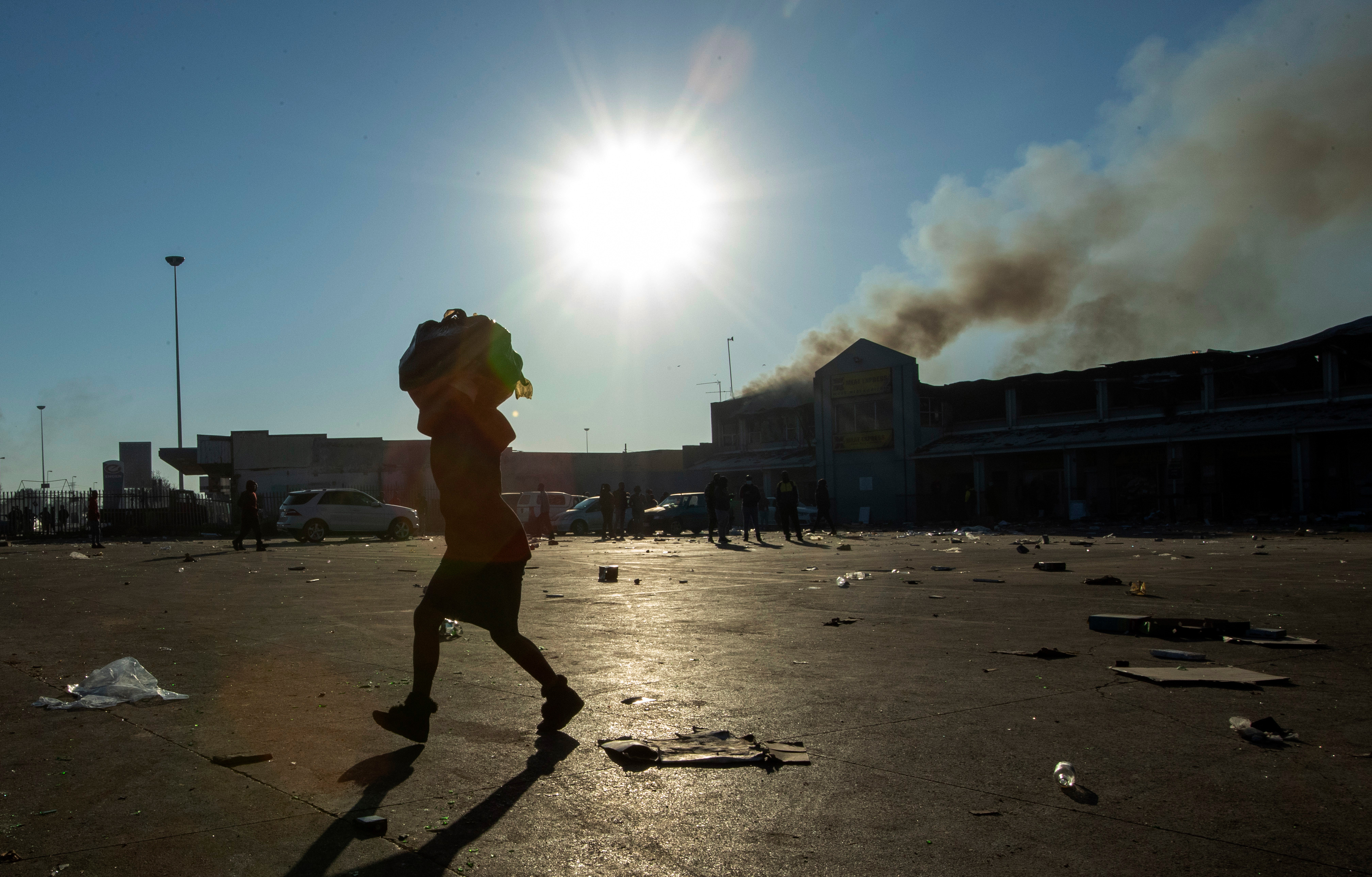 A woman carrying groceries looted from a nearby shop on her head at Naledi shopping complex in Vosloorus, east of Johannesburg, South Africa.