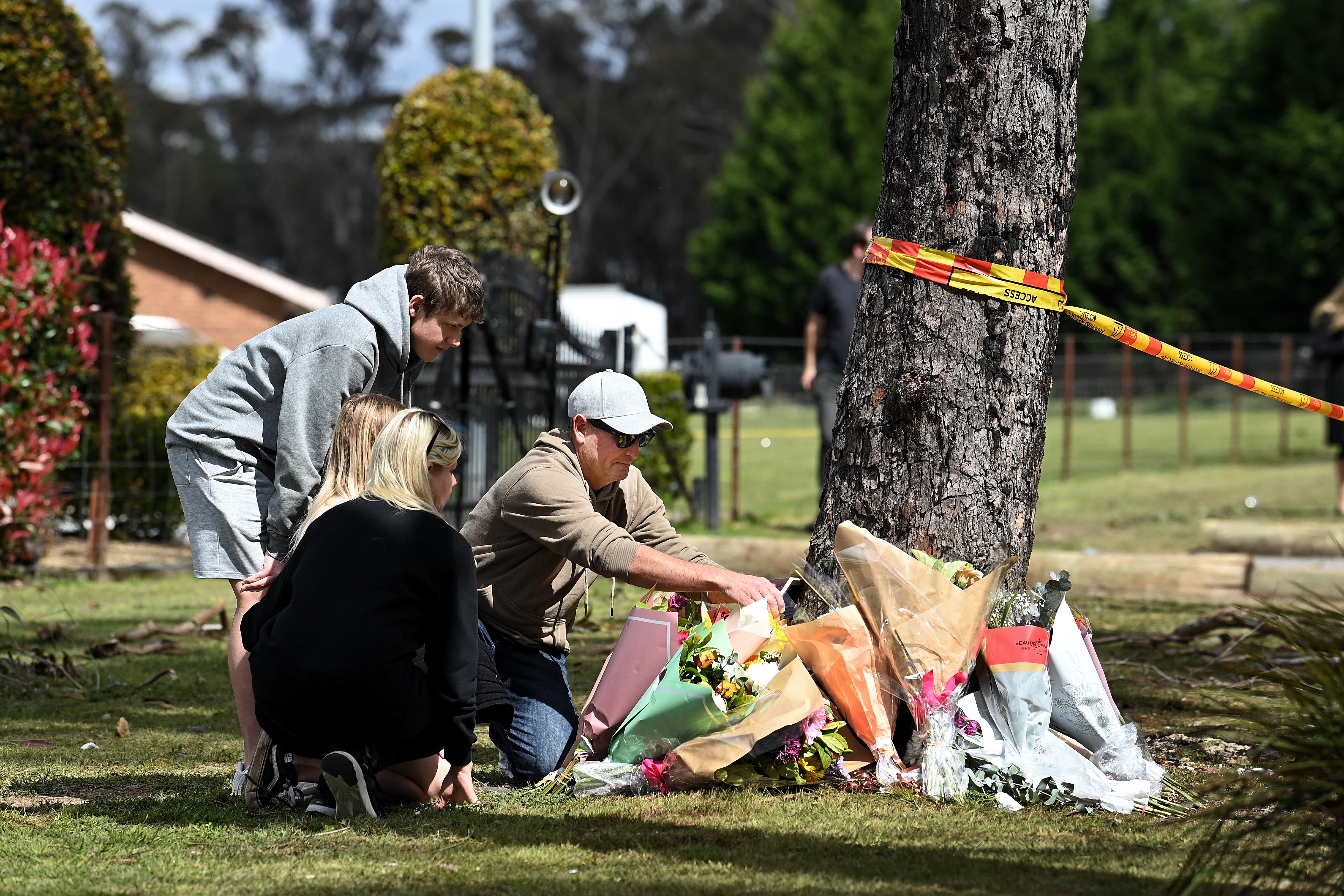 A family place a framed photo at the base of a tree where 5 people were killed in a motor vehicle accident last night on East Parade in Buxton, NSW. 7th September, 2022. Photo: Kate Geraghty