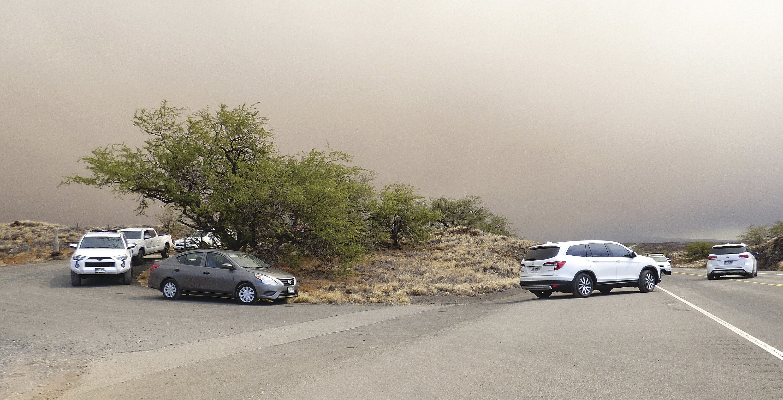 Vehicles turn onto Queen Kaahumanu Highway from an emergency access route opened after residents and visitors lodging in the Waikoloa Village area of Hawaii were ordered to evacuate. (Chelsea Jensen/West Hawaii Today via AP)