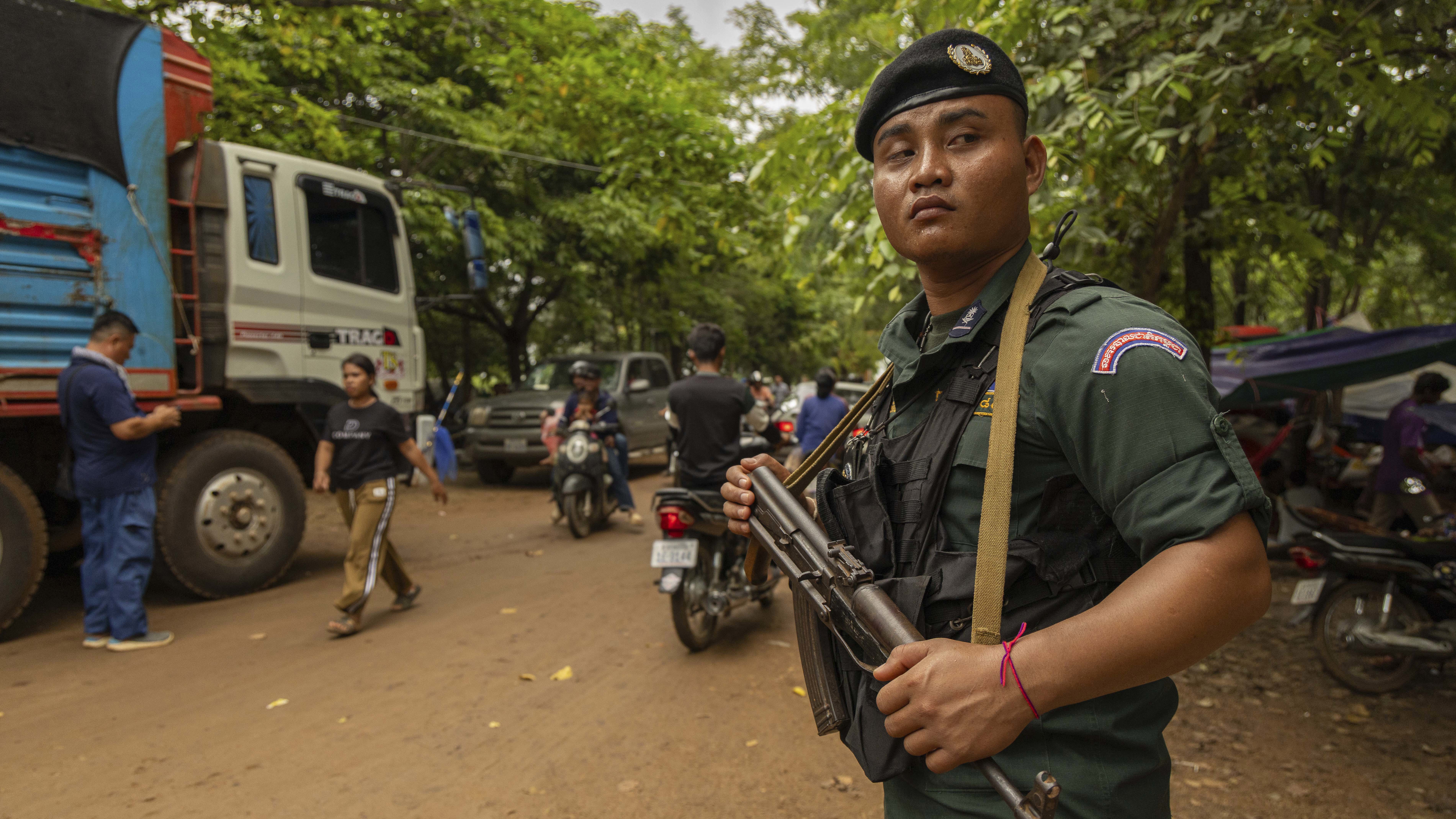 An armed Cambodian National Police officer protects a supply truck at a resettlement camp, established to house thousands of people fleeing the Thailand-Cambodia clash, in Oddar Meanchey, Cambodia, on Sunday, July 27, 2025