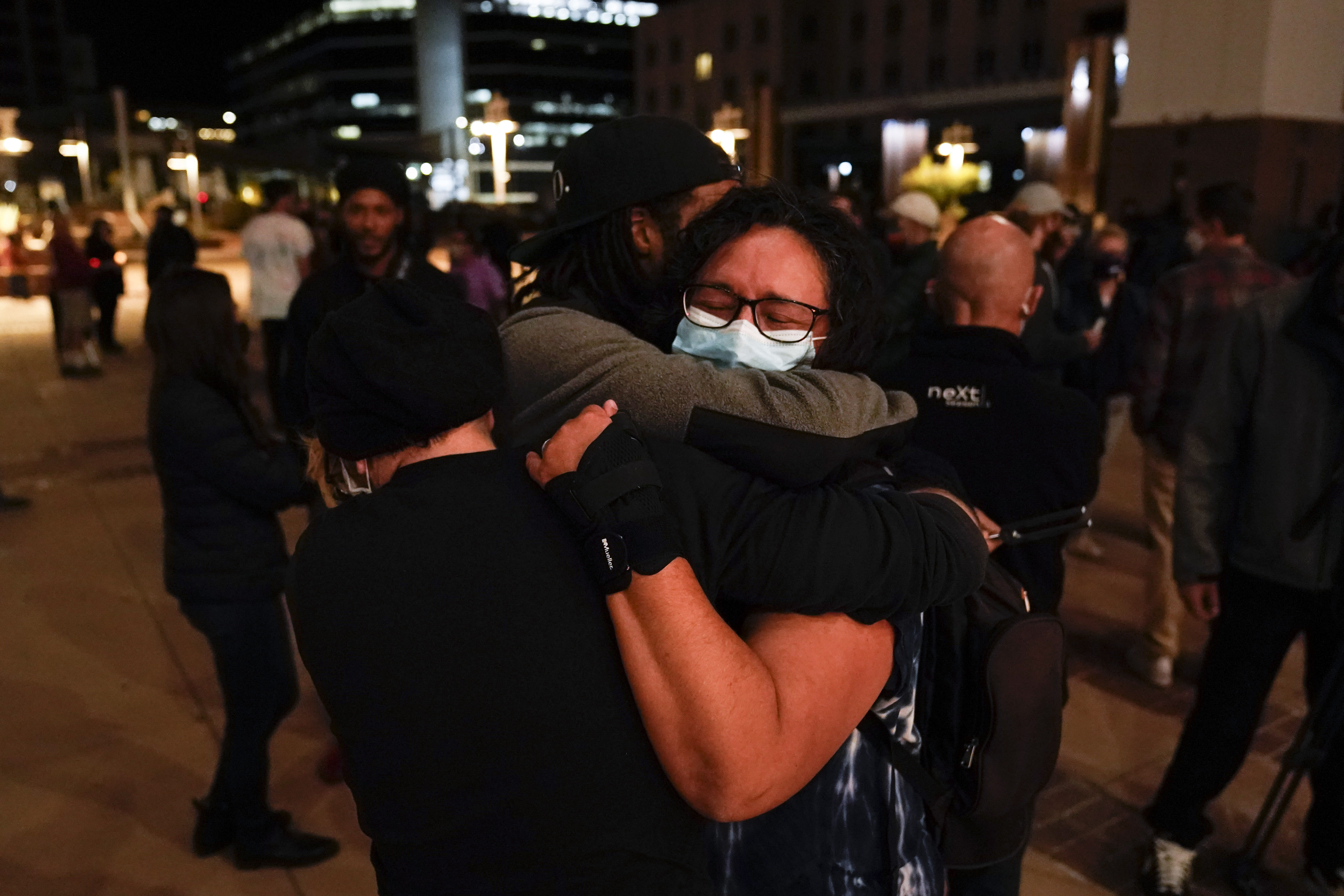 Three film industry workers comfort one another during the candlelight vigil. 