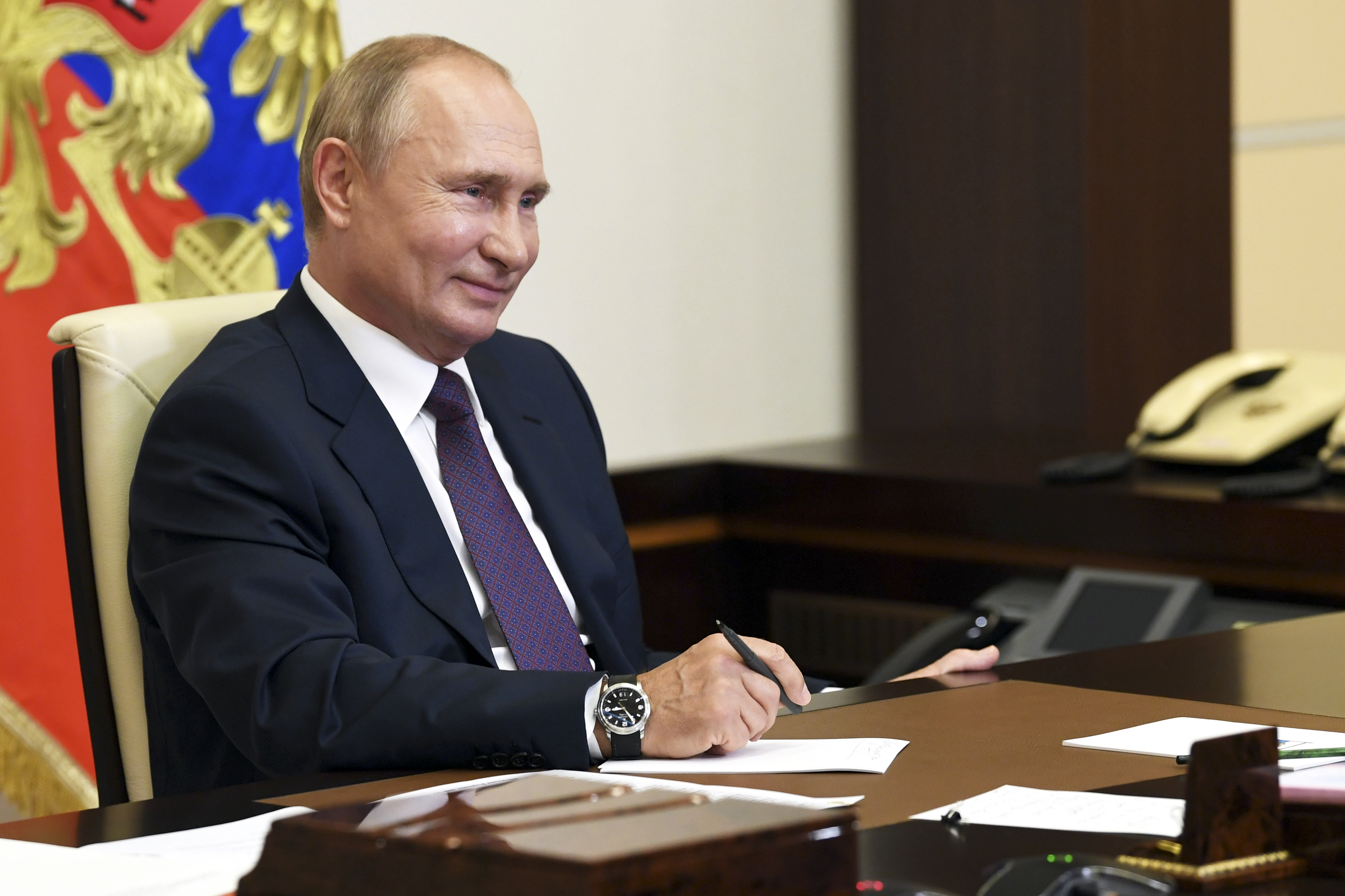 Russian President Vladimir Putin smiles as he attends a meeting via video conference at the Novo-Ogaryovo residence outside Moscow, Russia, Thursday, Aug. 20, 2020.