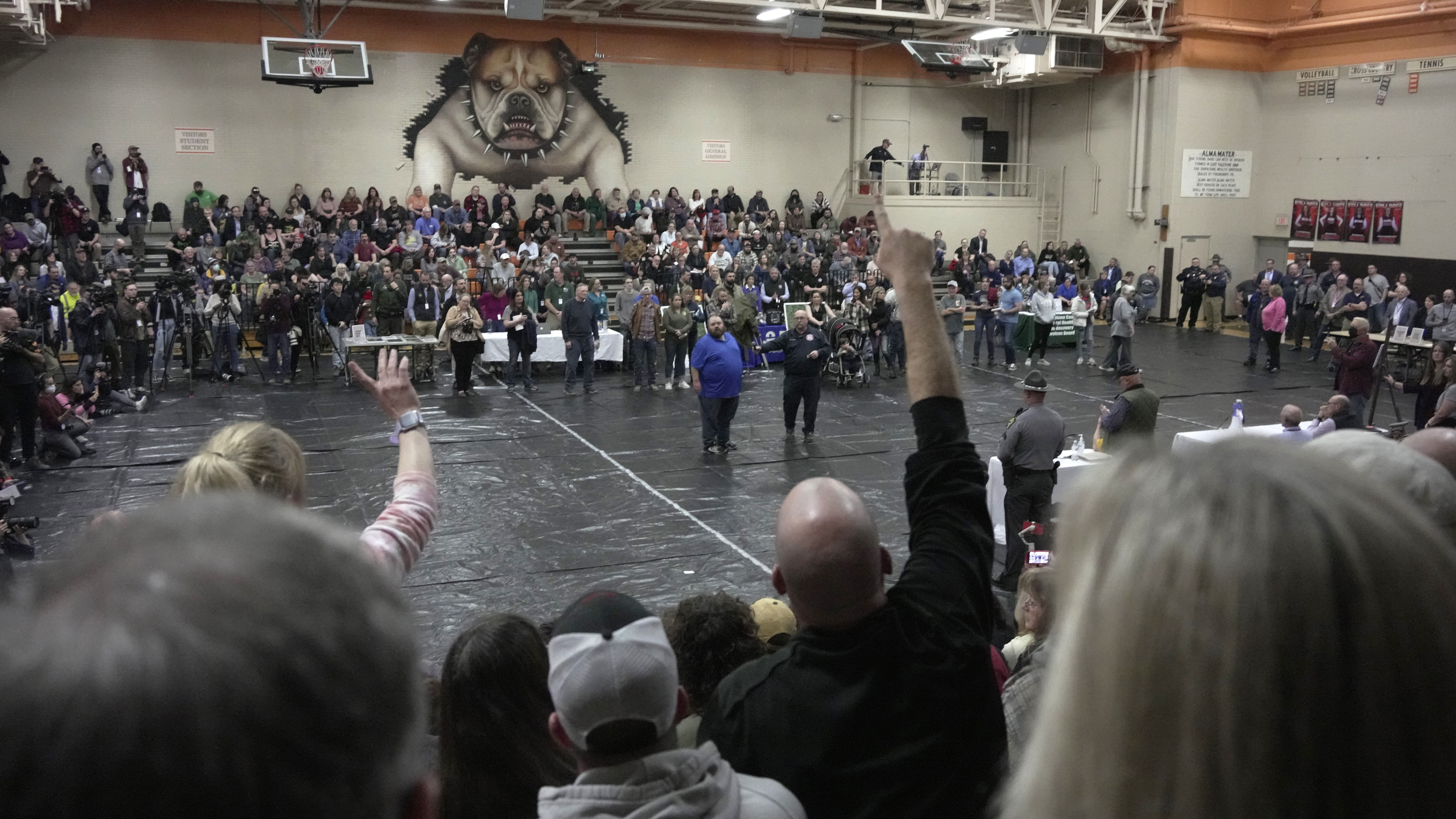 A man raises his hand with a question for East Palestine, Ohio Mayor Trent Conaway, center, during a town hall meeting at East Palestine High School in East Palestine, Ohio, Wednesday, Feb. 15, 2023. The meeting was held to answer questions about the ongoing cleanup from the derailment on Feb, 3, of a Norfolk Southern freight train carrying hazardous material. (AP Photo/Gene J. Puskar)