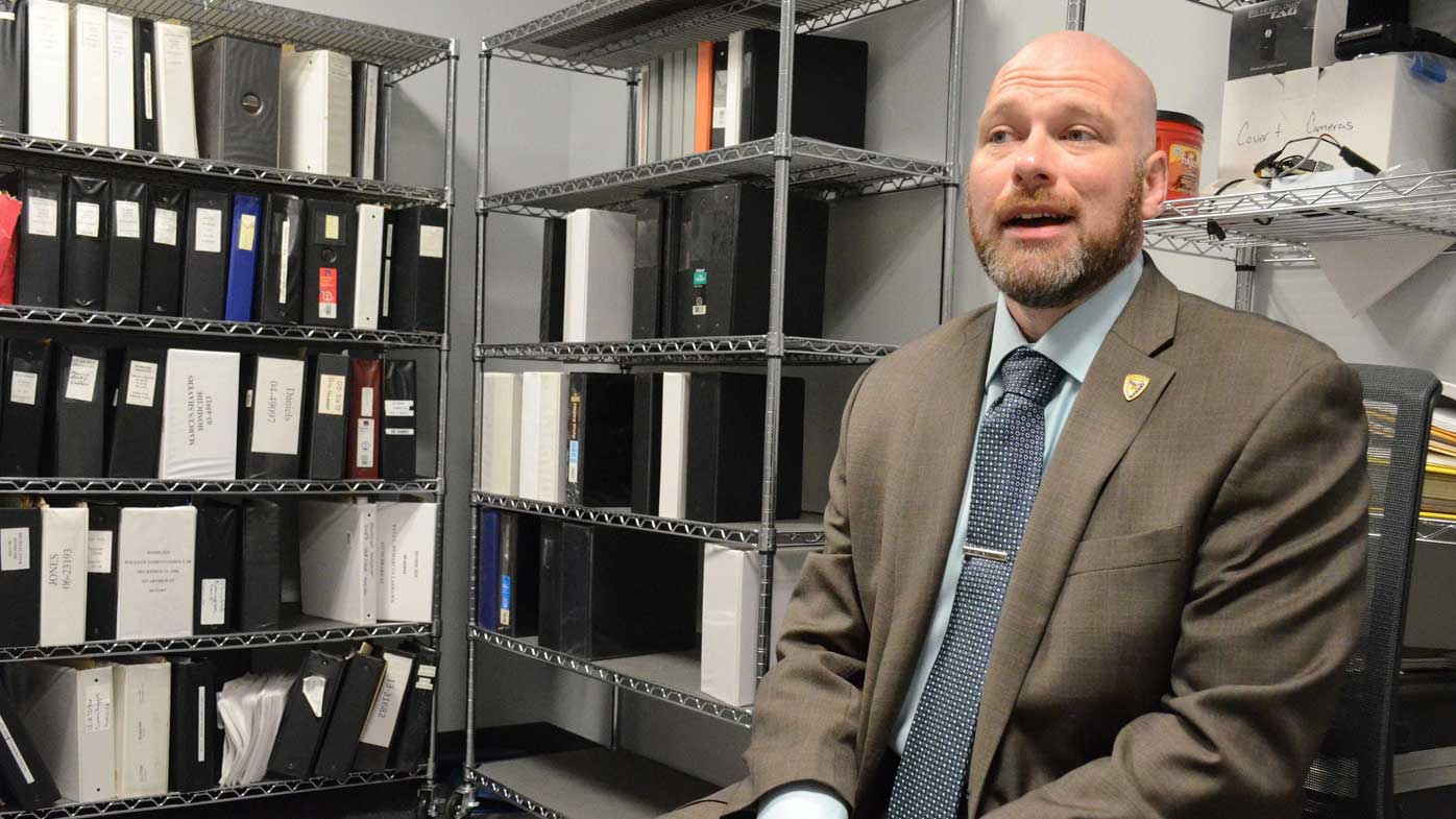 Detective Scott Marshall poses with some of the cold case files at the Battle Creek Creek Police Department.
