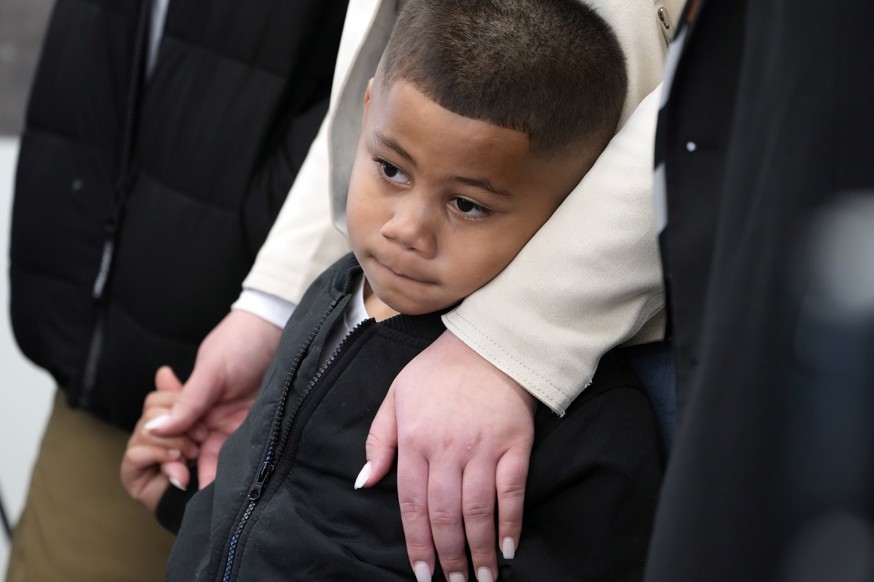 Syncere Kai Anderson, 5, is held by his mother, Gabrielle Hansell, as he listens laywers Benjamin Crump, and Carl Douglas.