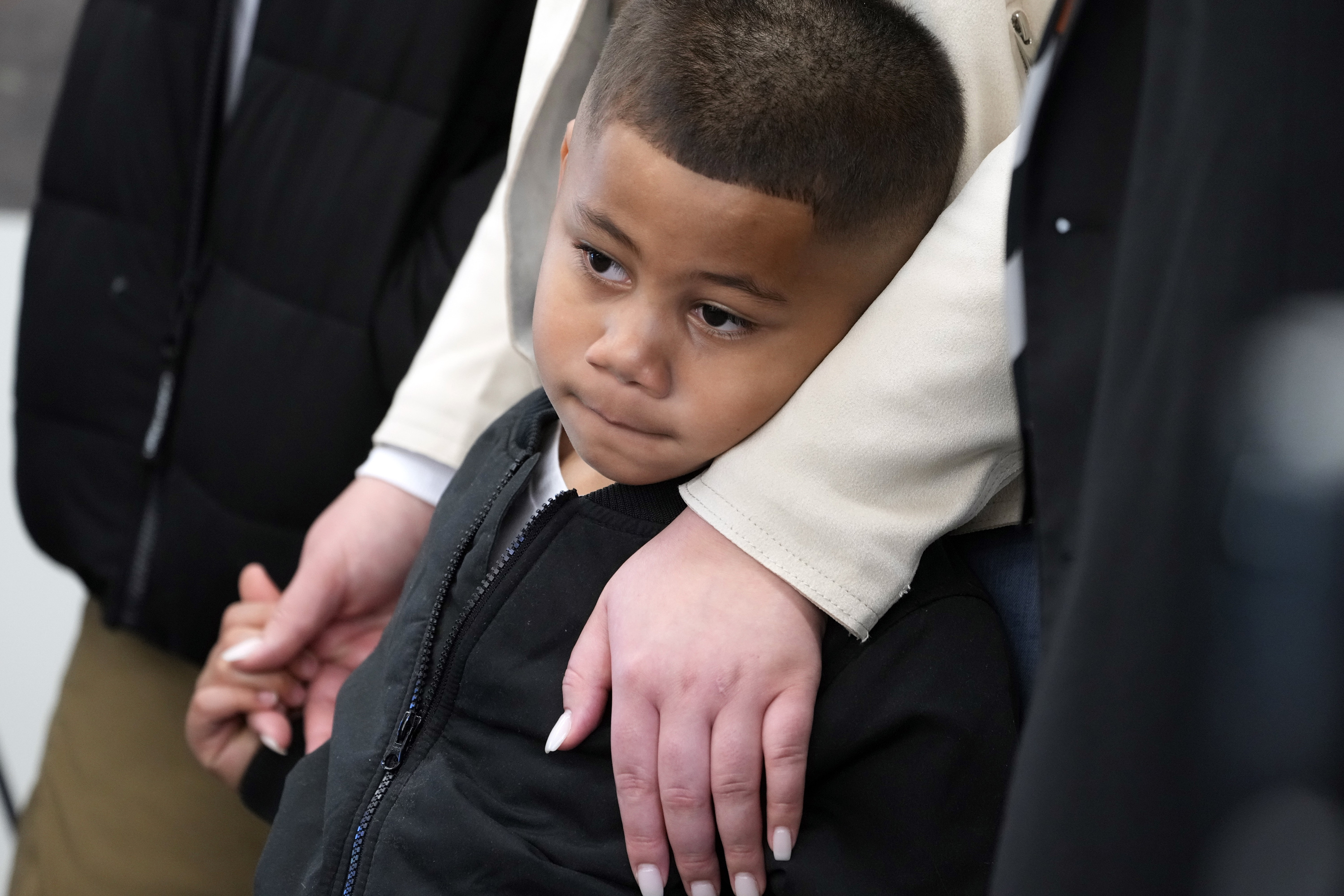 Syncere Kai Anderson, de 5 años, está en brazos de su madre, Gabrielle Hansell, mientras escucha a los abogados Benjamin Crump y Carl Douglas.