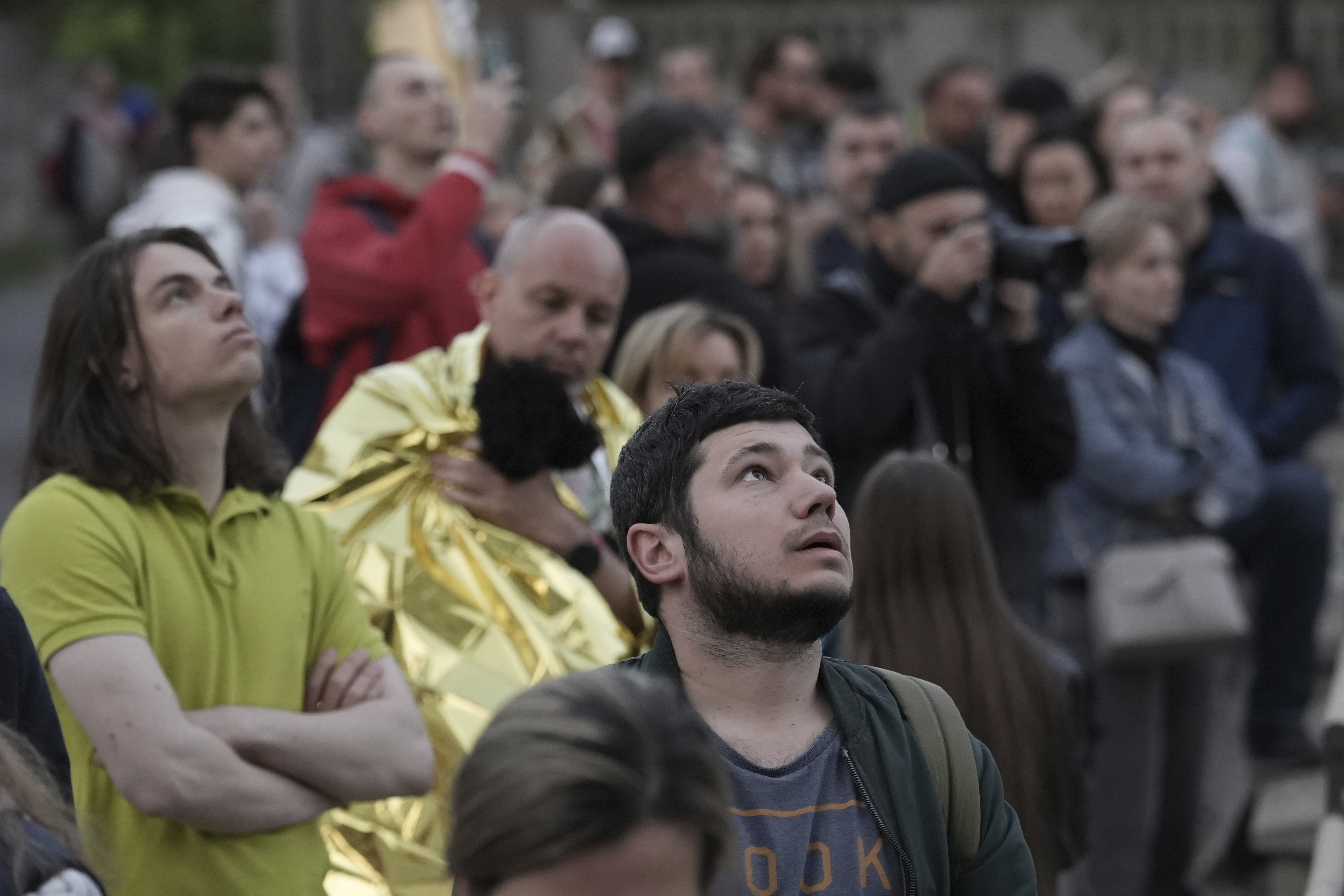 Evacuated residents look at their multi-story apartment building which was damaged during Russian attack in Kyiv, Ukraine, Tuesday, May 30, 2023. 