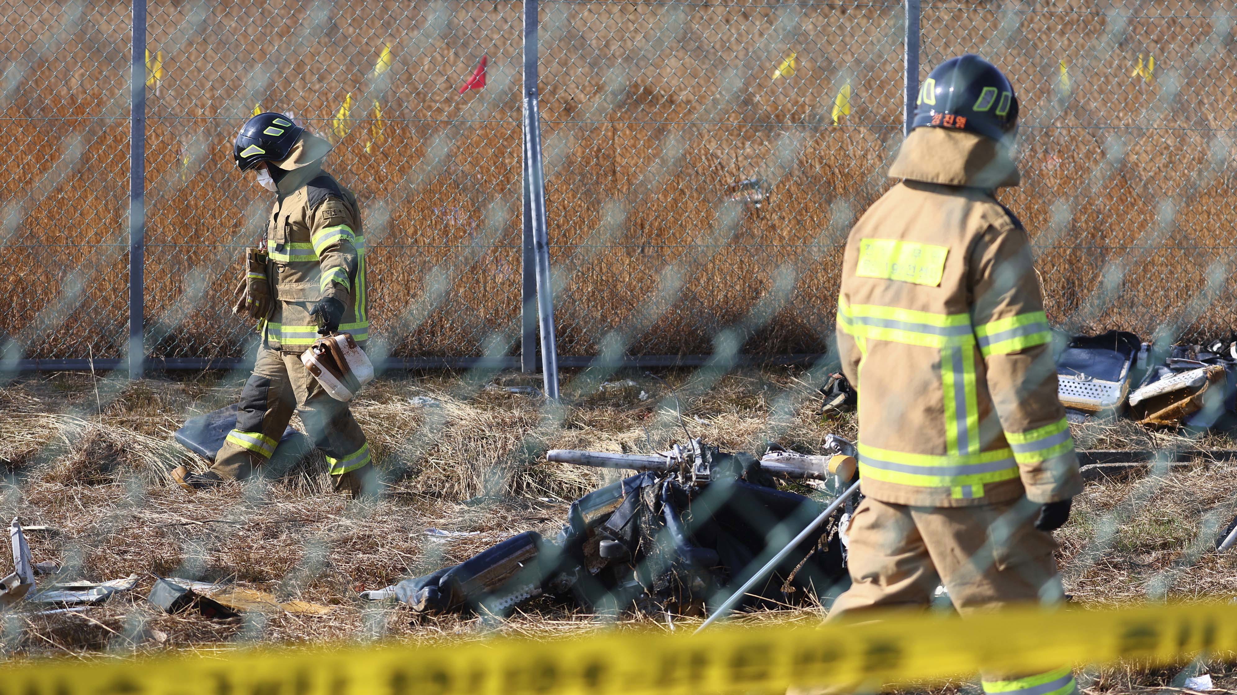 Firefighters search near the debris at the site of a plane fire at the Muan International Airport in Muan, South Korea,