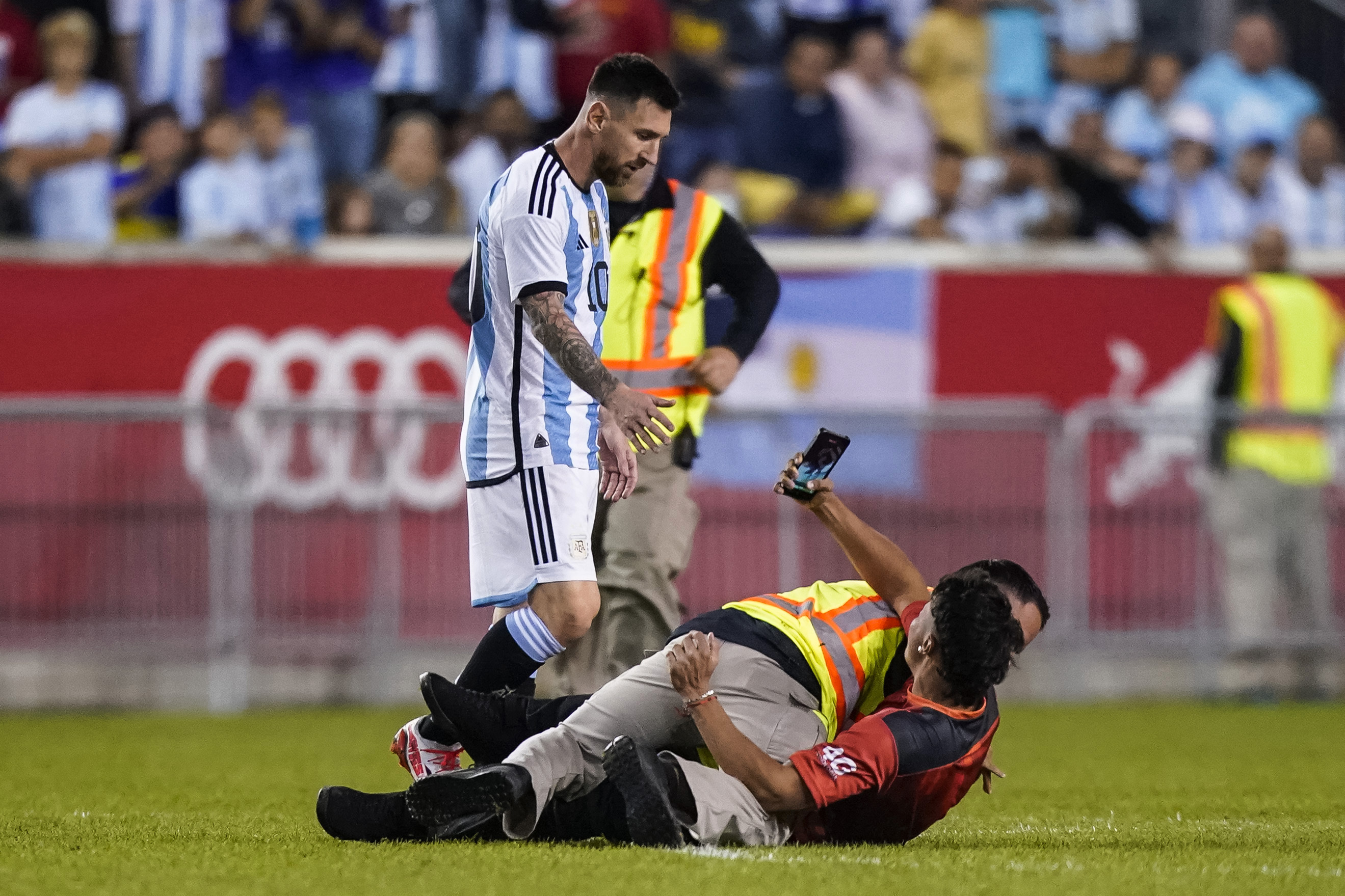 A fan is tackled as he tries to take a picture of Argentina's Lionel Messi.