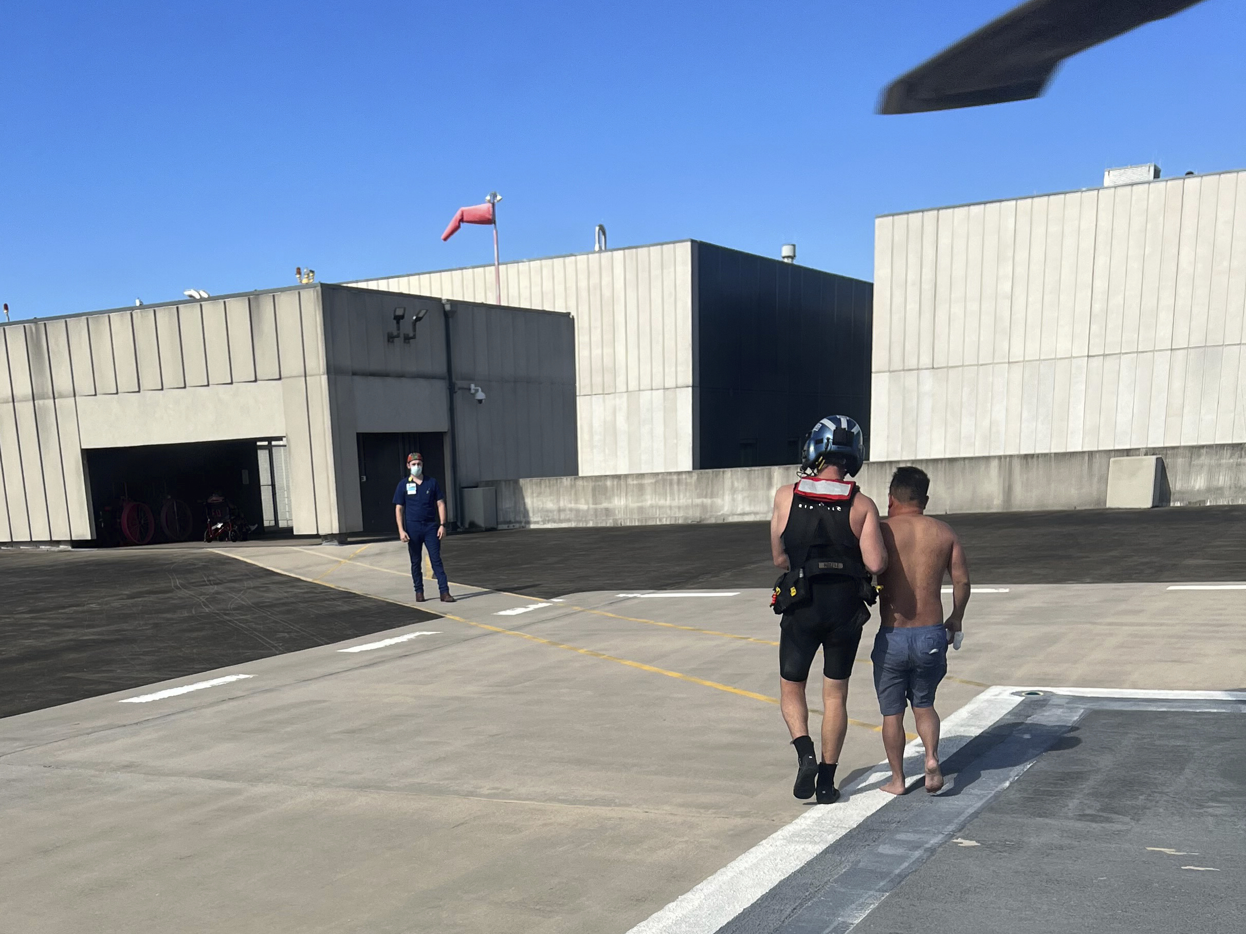 In this image provided by the U.S. Coast Guard, a Coast Guard Station New Orleans rescue swimmer escorts a rescued boater into University Medical Center New Orleans on Sunday, Oct. 9, 2022, in New Orleans, La. Three men whose fishing boat sank in the Gulf of Mexico off the Louisiana coast were rescued after surviving for more than a day despite being attacked by sharks that inflicted deep cuts on their hands and shredded one of their life jackets, according to their rescuers. 