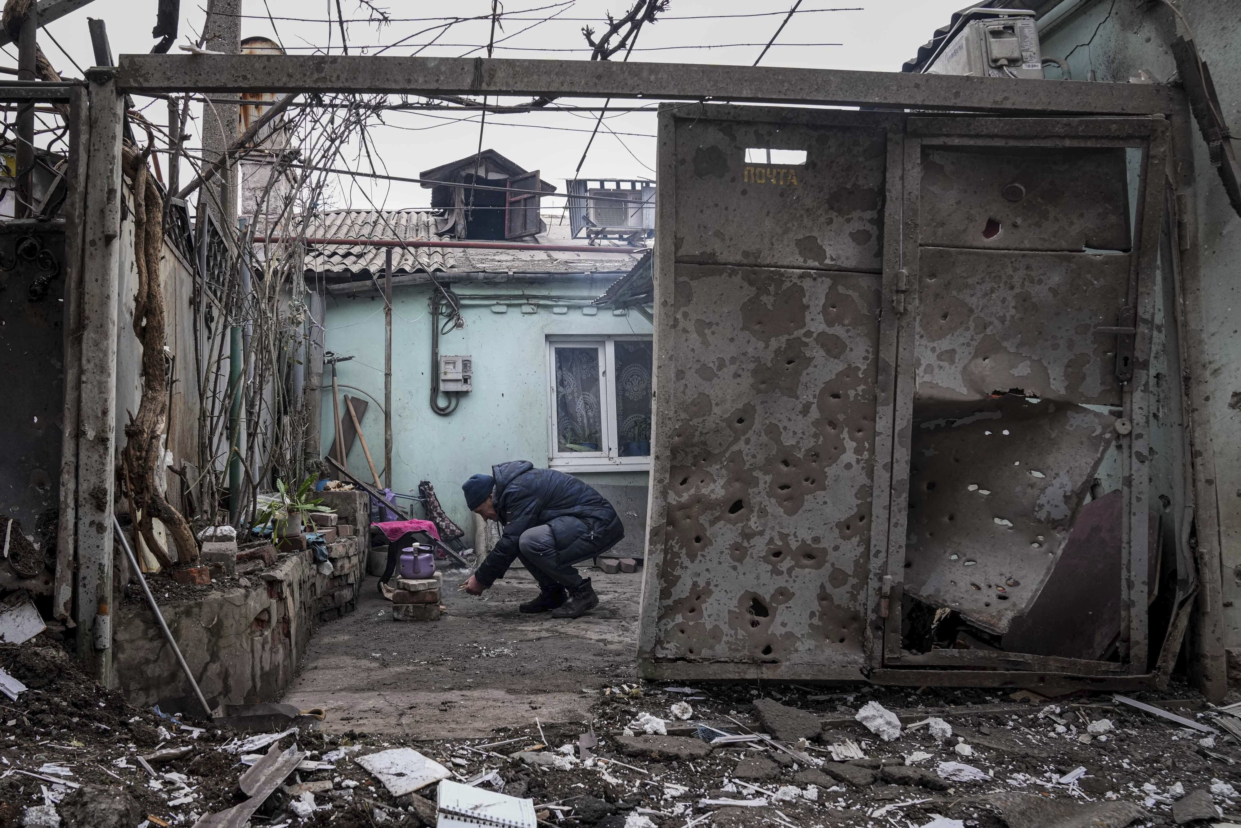 A man lights a fire under the kettle in a yard of an apartment building hit by shelling in Mariupol, Ukraine, Monday, March 7, 2022.